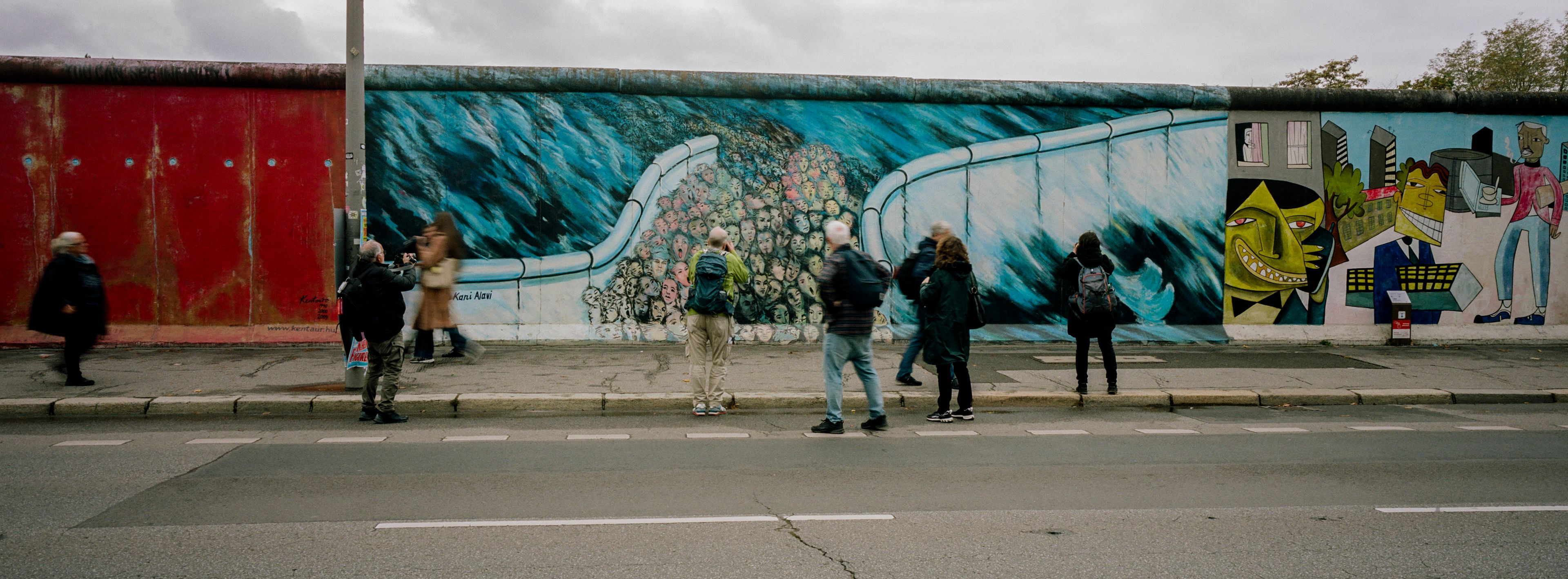 People gather at a painting at the so-called East Side Gallery, a popular place for street art on remains of the Berlin Wall in Berlin, Germany, Wednesday, Oct. 30, 2024. (AP Photo/Markus Schreiber)