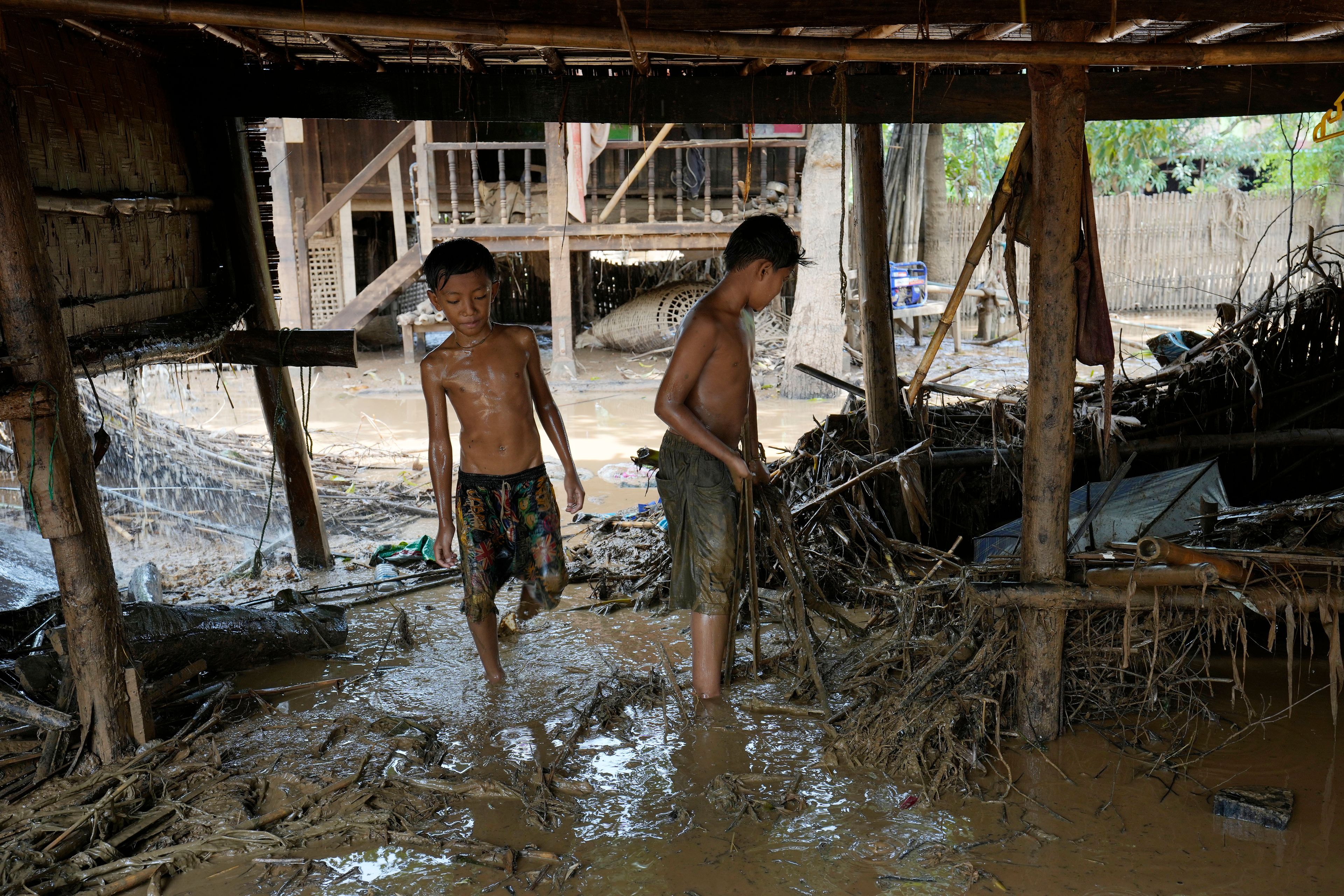 Boys try to clean up the debris from a flooding at home in Naypyitaw, Myanmar, Wednesday, Sept. 18, 2024. (AP Photo/Aung Shine Oo)