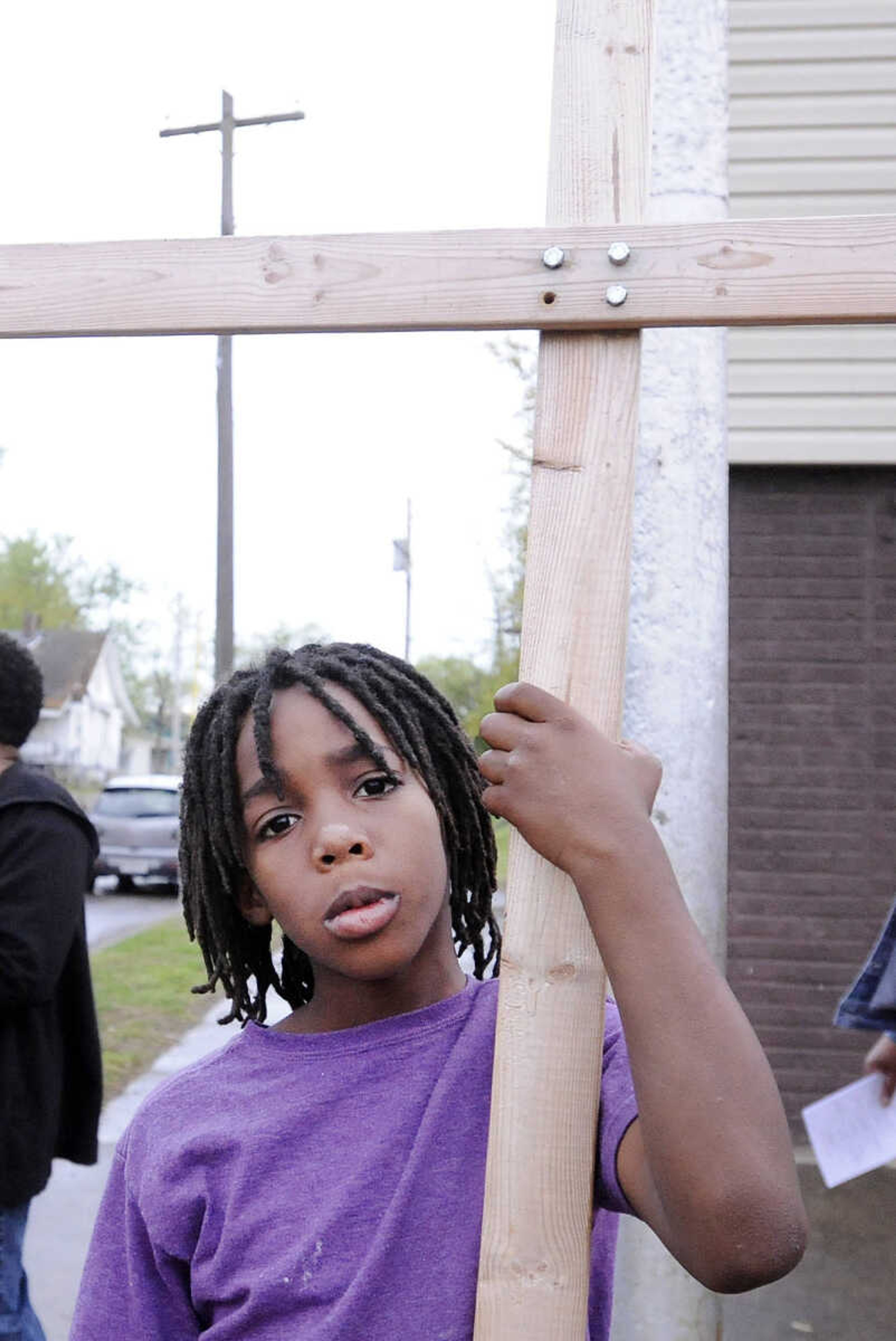 LAURA SIMON ~ lsimon@semissourian.com

Javion Hamilton, 8, holds a wooden cross Thursday evening, April 14, 2016, during a prayer vigil on Locust Street in Cape Girardeau. Felice Roberson organized the vigil for Airious Darling who was shot and killed on Locust Street on March 31. Roberson's son Quinton Combs was shot and killed in November 2015 on Frederick Street.