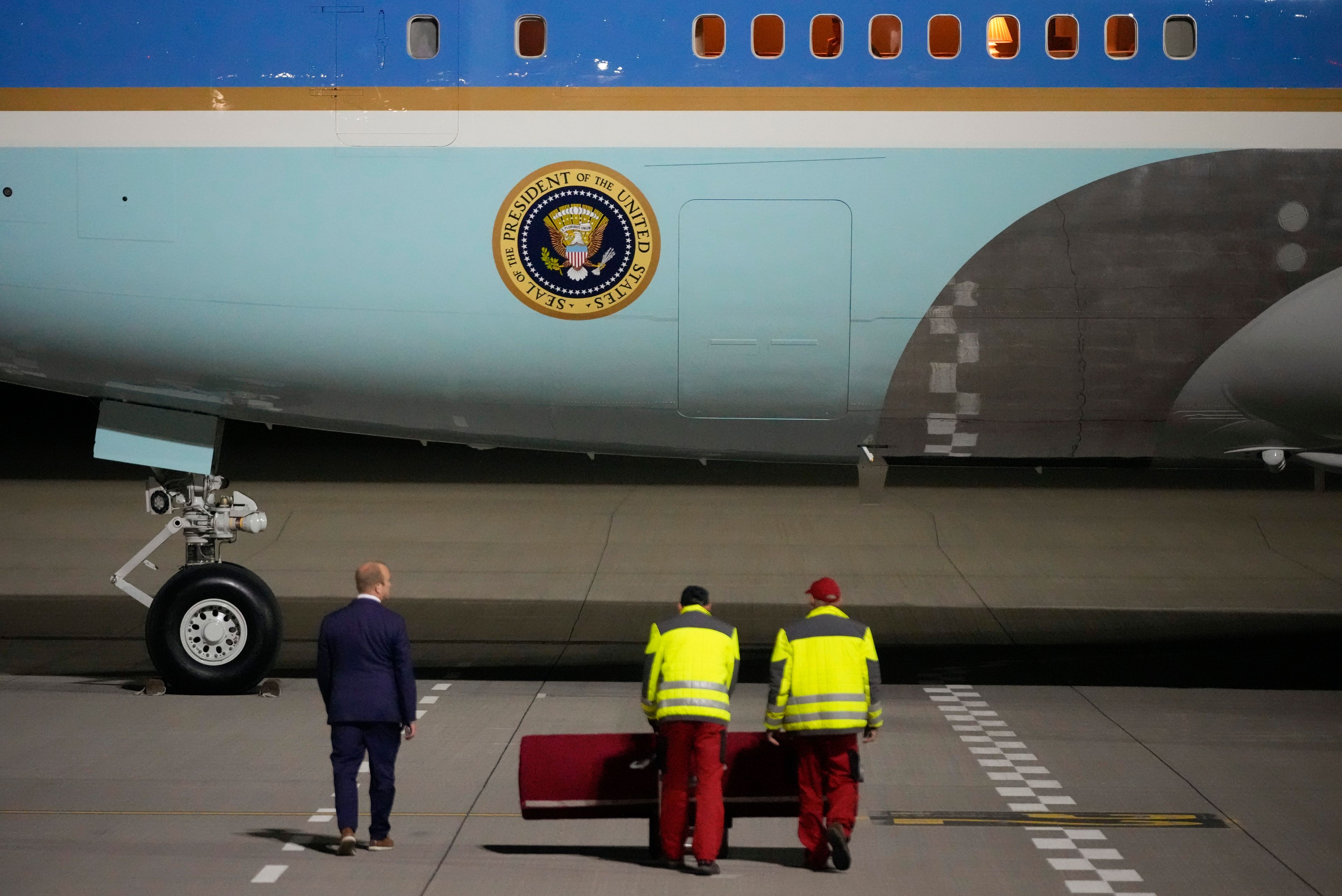 Workers wheel out the red carpet as President Joe Biden arrives on Air Force One at Brandenburg Airport in Schoenefeld near Berlin, Germany, Thursday, Oct. 17, 2024. (AP Photo/Matthias Schrader)