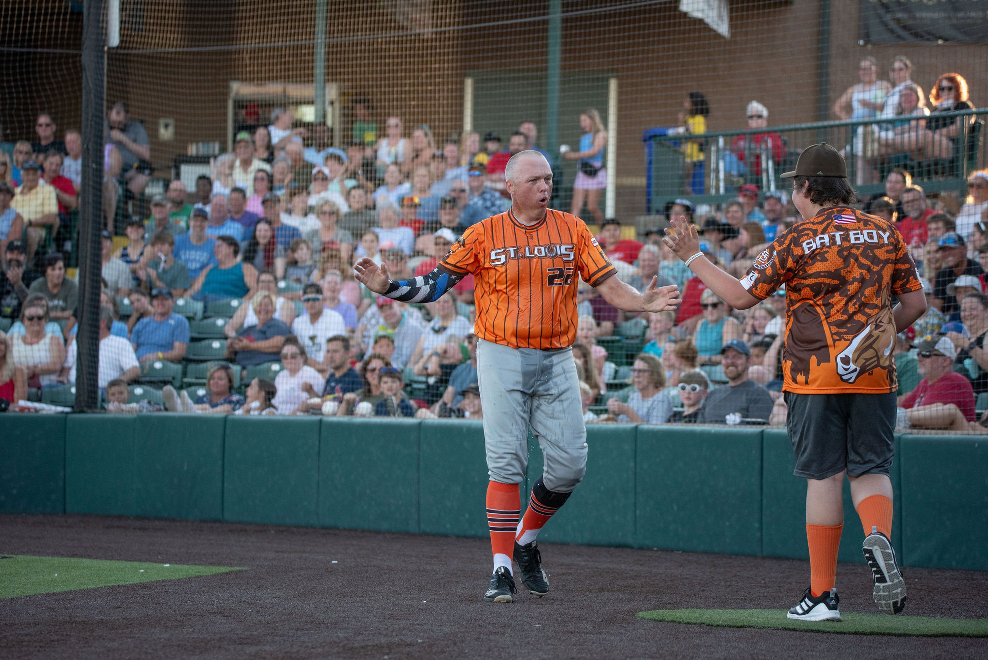 St. Louis Clydesdales co-founder and St. Peter’s Police Department patrolman John Aebischer goes to slap hands with a bat boy after dousing himself with water during the team’s “Hootenanny” exhibition at CarShield Field in O’Fallon. 