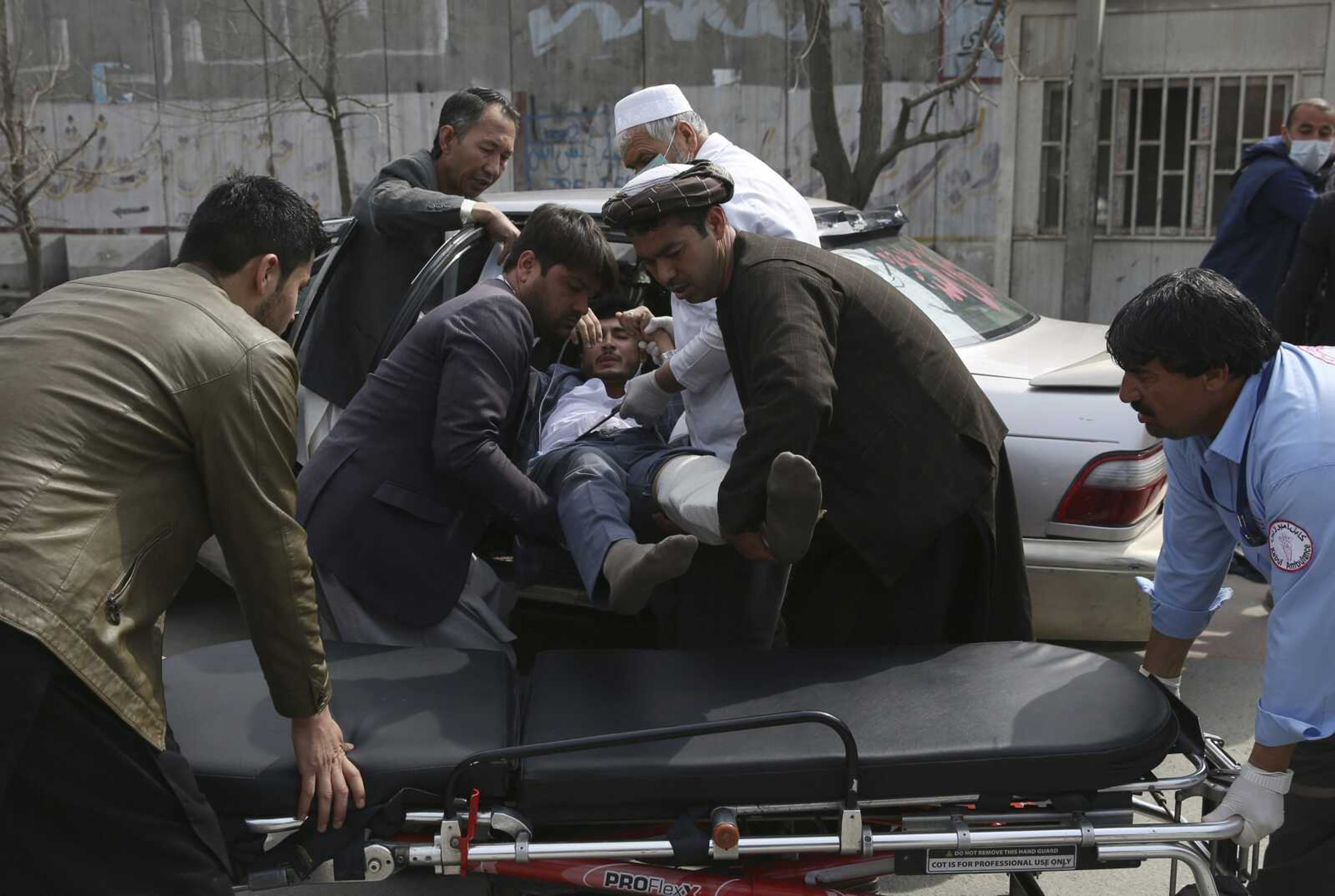 An injured man is carried into an ambulance Friday after an attack in Kabul, Afghanistan.  Gunmen in Kabul attacked a remembrance ceremony for a minority Shiite leader.