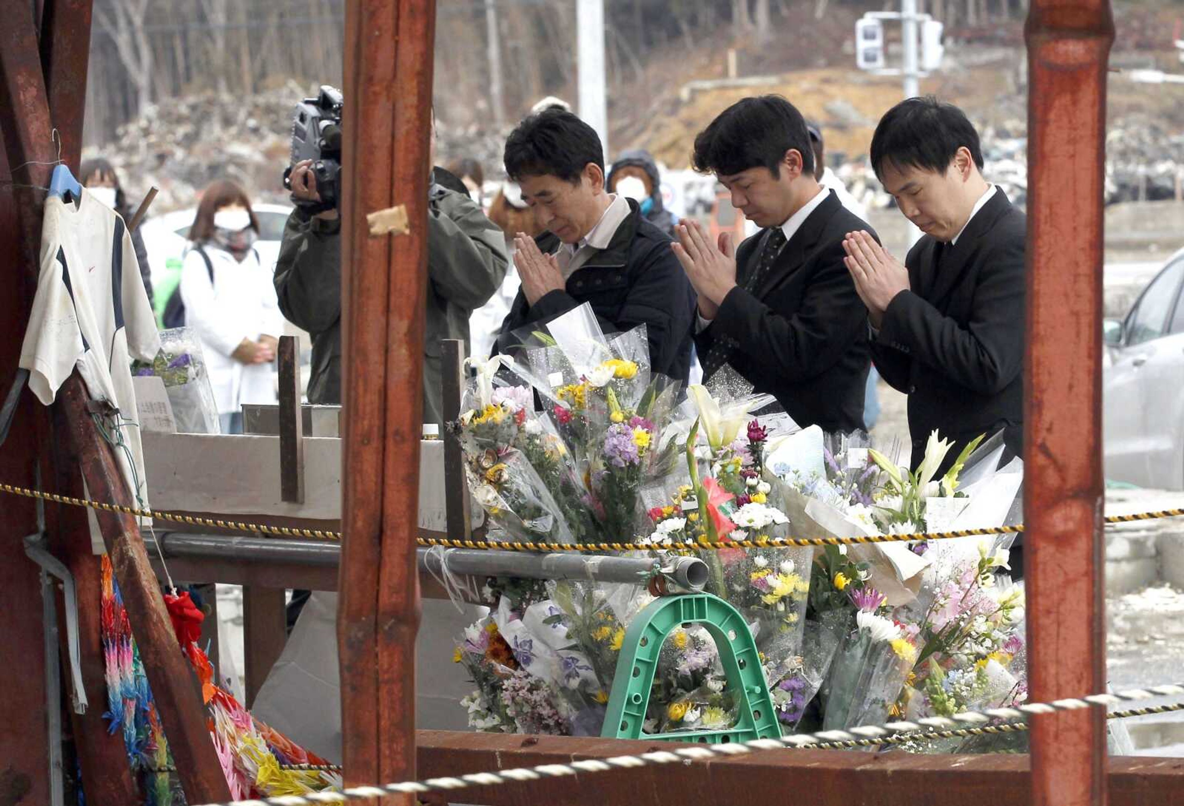 People offer prayers Sunday in front of what&#8217;s left of the disaster control center in the area devastated by the March 11, 2011, earthquake and tsunami, in Minamisanriku, Japan. (Shizuo Kambayashi ~ Associated Press)