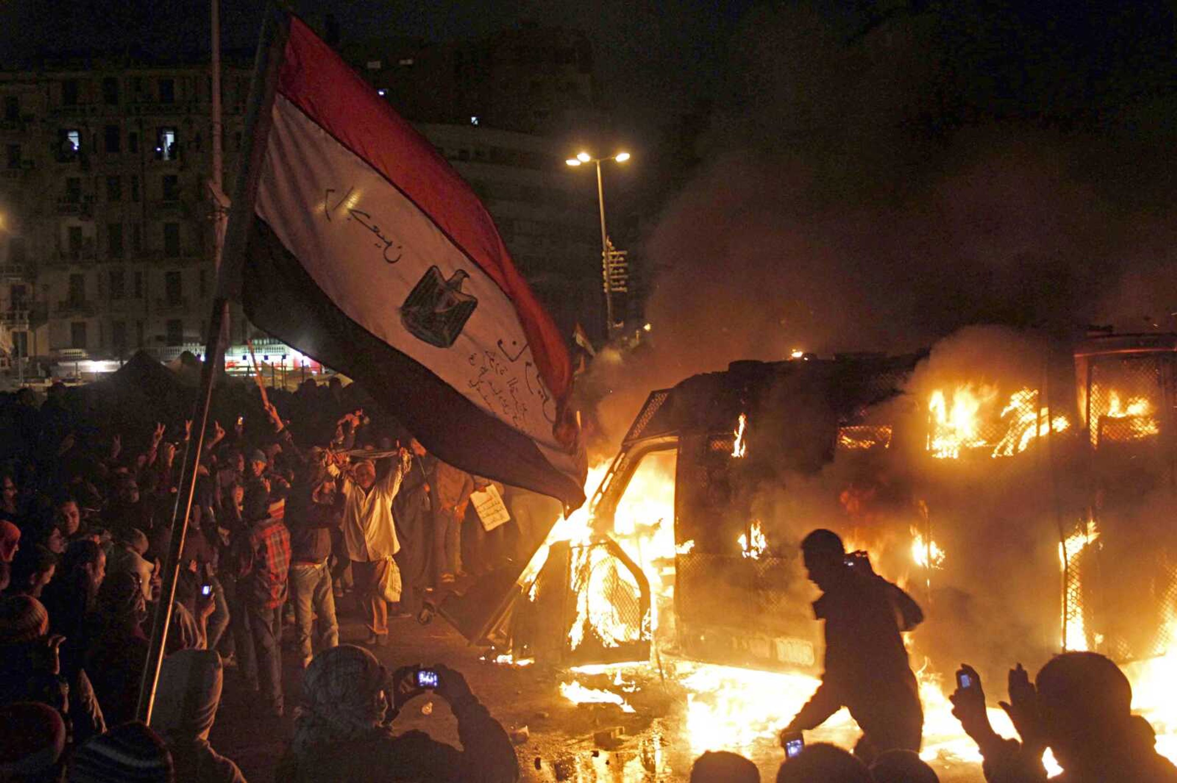 Egyptian protesters use camera phones to take photos of a burning state security armored vehicle Monday in Cairo. Demonstrators commandeered the vehicle during clashes with security forces nearby and brought it to Tahrir Square and set it alight. (Mostafa El Shemy ~ Associated Press)