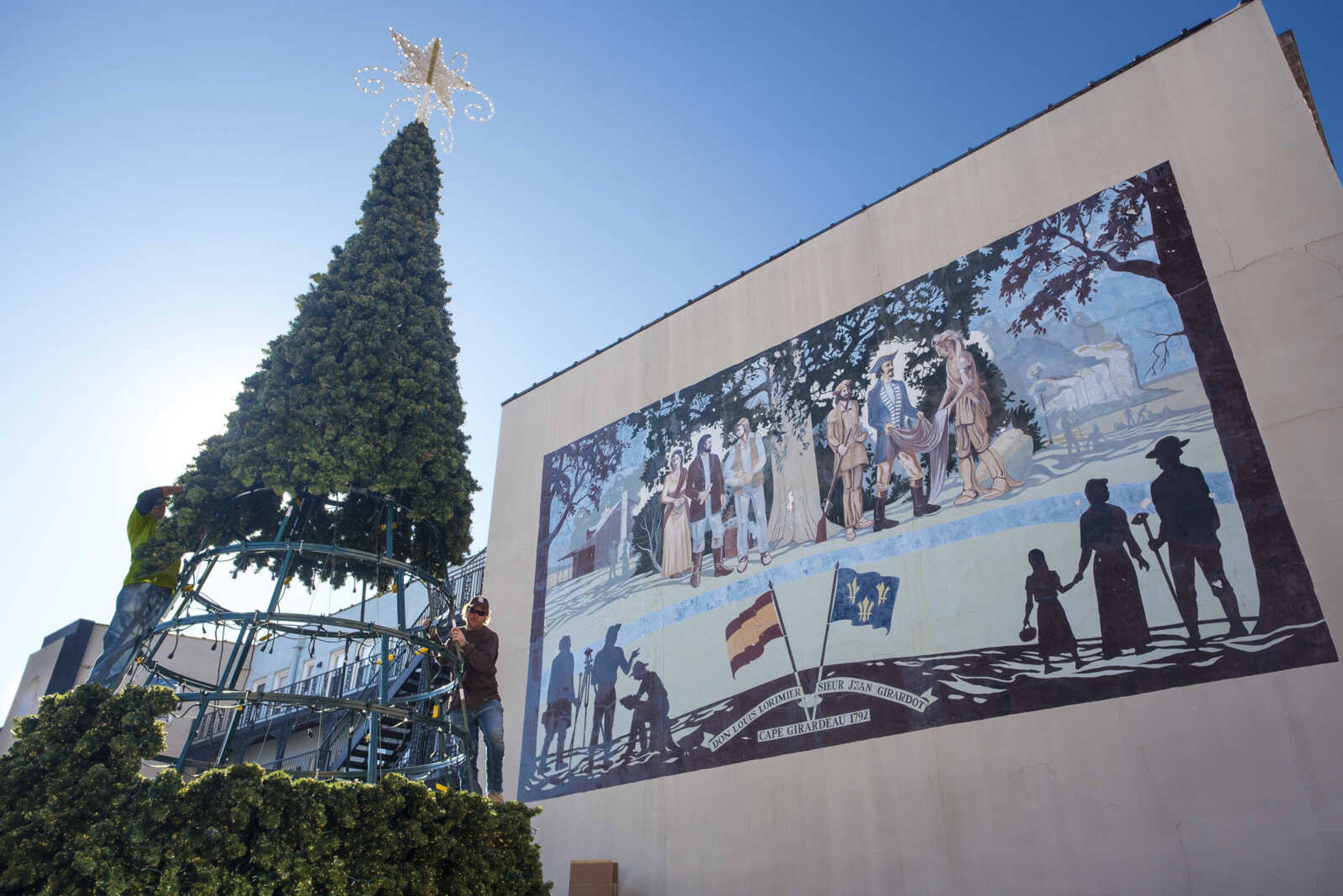 Forck's Lite Designs & Guttering  decorators C.B. Forck, center left, and his son Brent, far left, piece together a 30-foot Christmas tree Monday, Nov. 25, 2019, at the courtyard of Vasterling Suites in Cape Girardeau.