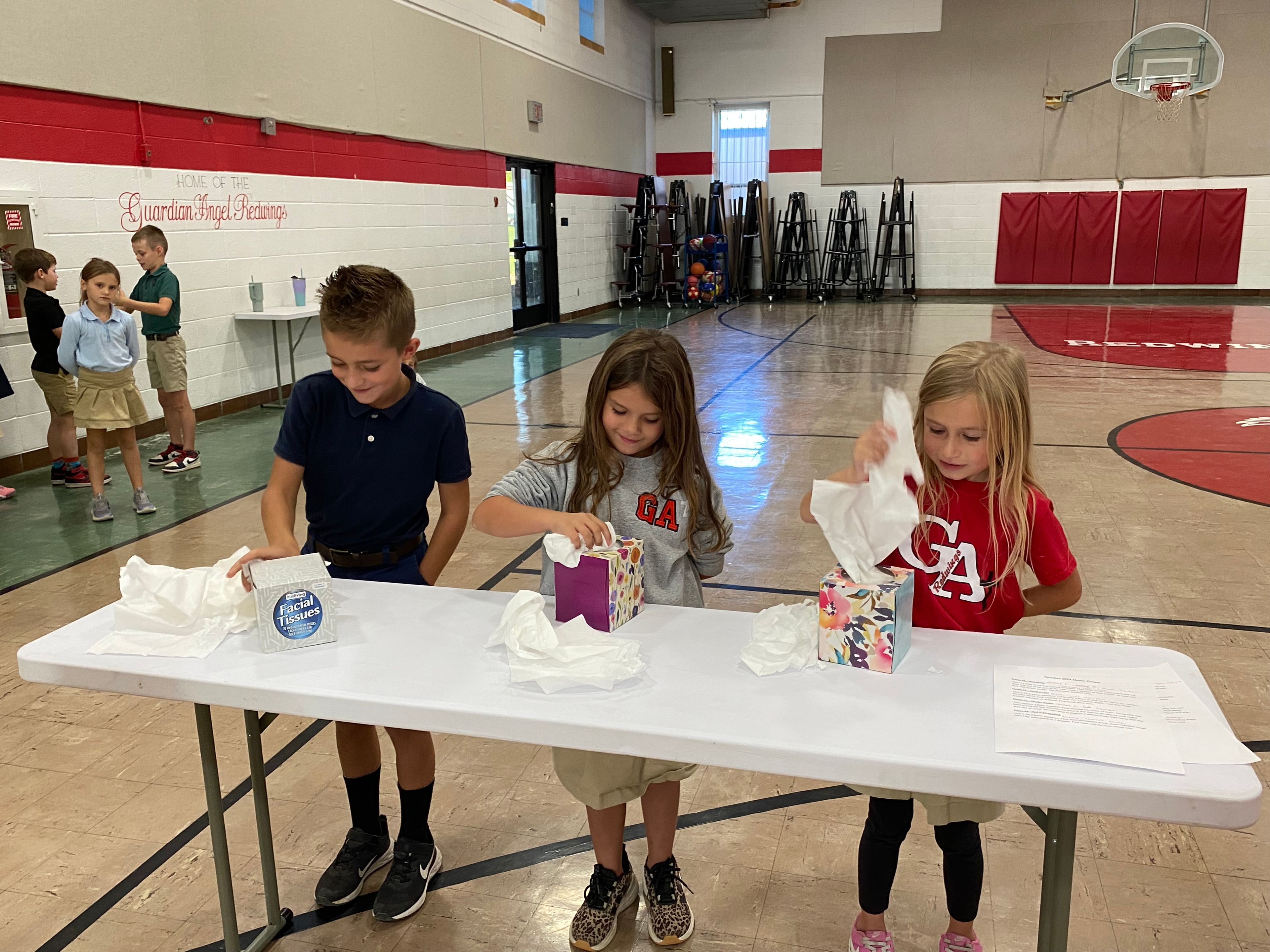 Sawyer Dirnberger, Caroline Eskew, and Caroline Kyle of St. Raphael's house try to speed through the pulling of tissues from a tissue box in an effort to be declared the winners of the game "Hanky Panky”.