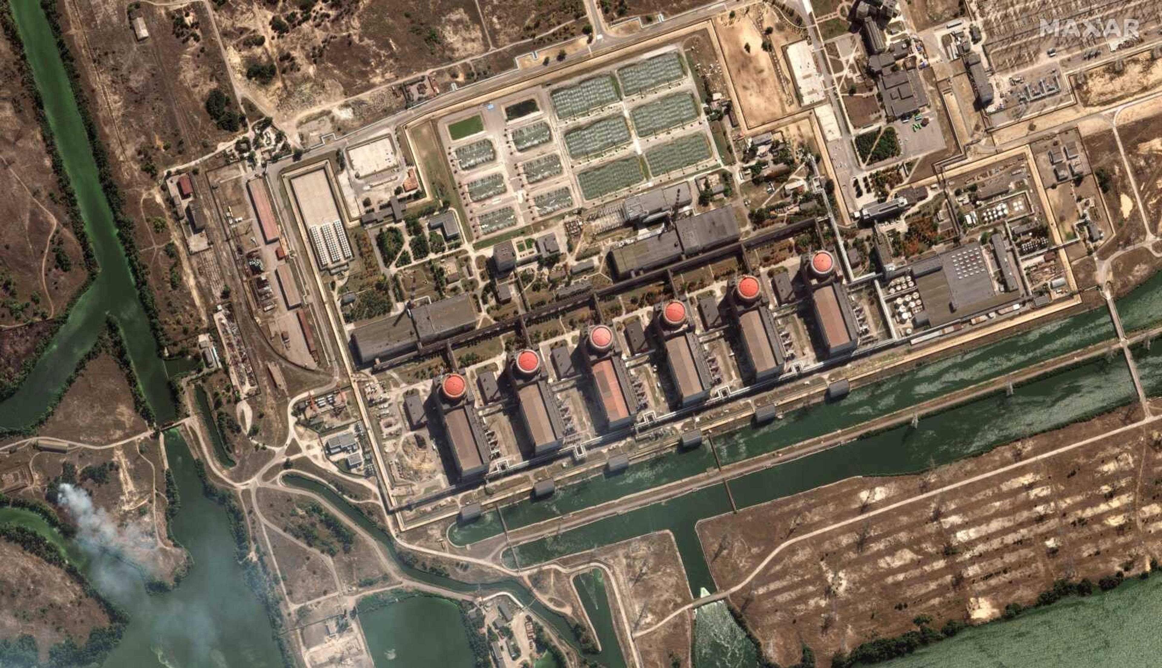 This satellite image provided by Maxar Technologies shows bush fires Monday outside of the main power plant facilities at the Zaporizhzhia nuclear plant in Russian-occupied Ukraine. A team from the U.N. nuclear watchdog on Monday started its journey to the plant at the heart of fighting in Ukraine, a long-awaited mission to inspect crucial safety systems.