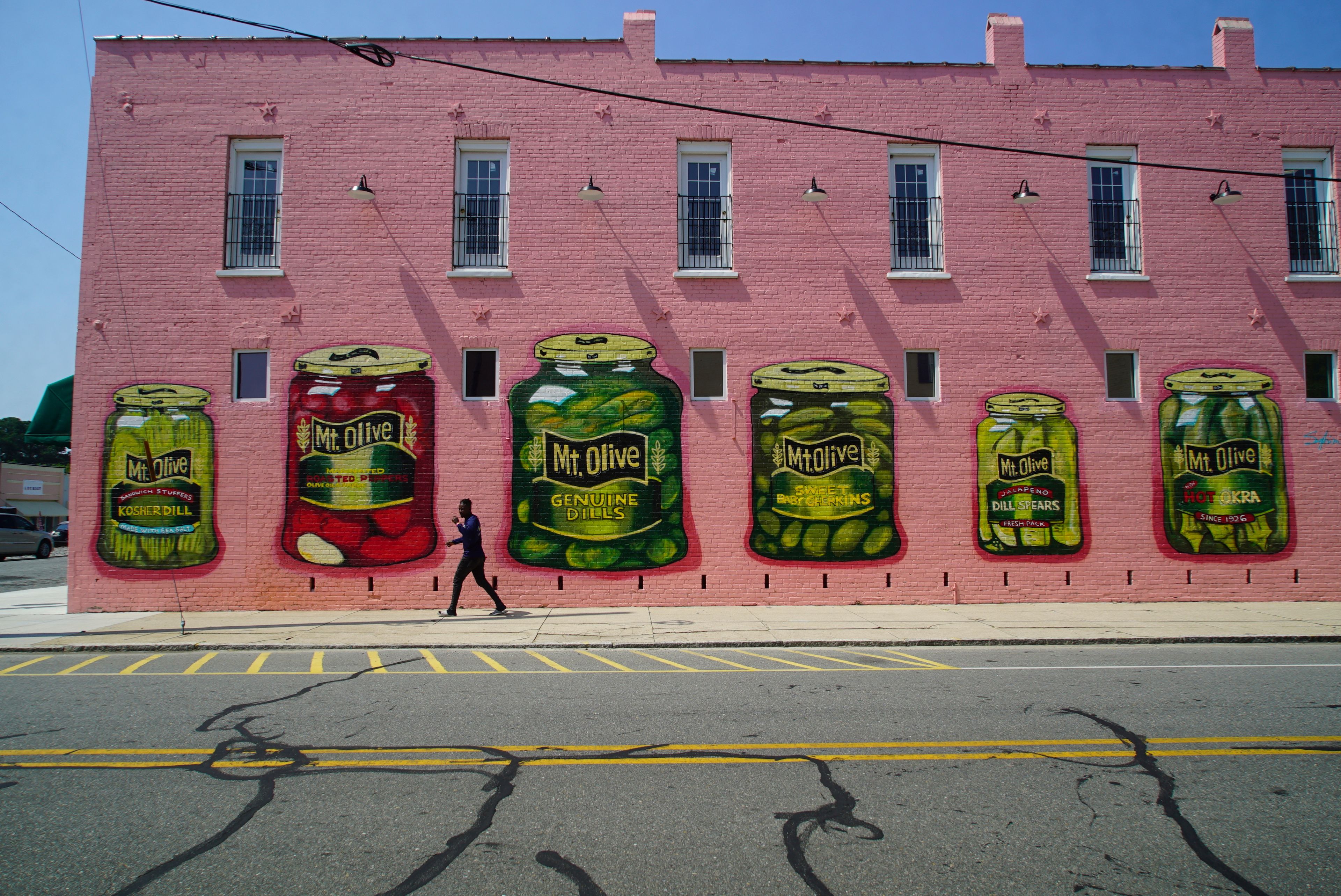 A man walks past a mural of various pickle products in Mount Olive, N.C., on Monday, July 15, 2024. (AP Photo/Allen G. Breed)