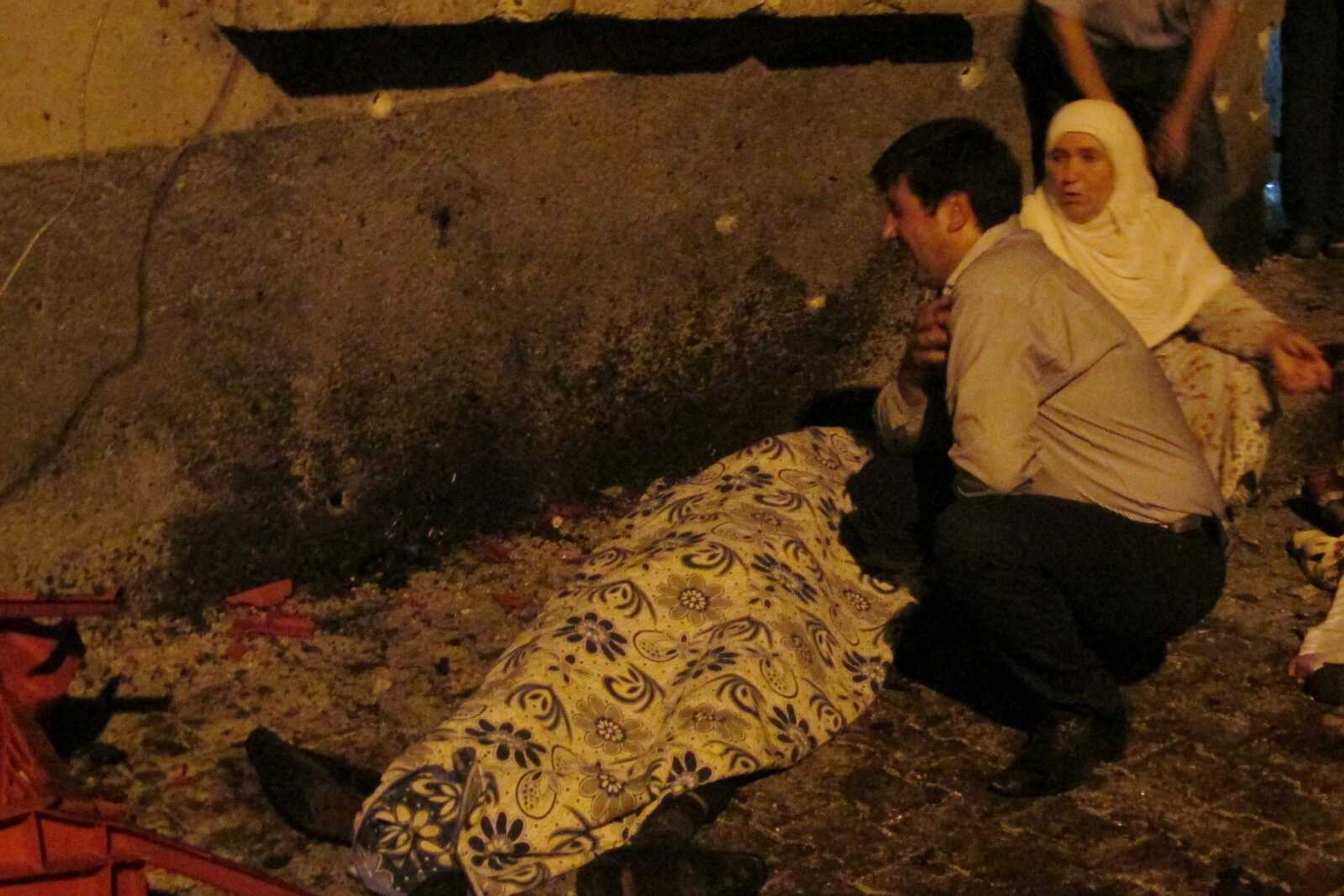 A man cries over a covered body after an explosion Saturday in Gaziantep, Turkey. Gaziantep province Gov. Ali Yerlikaya said the deadly blast, during a wedding near the border with Syria, was a terror attack.