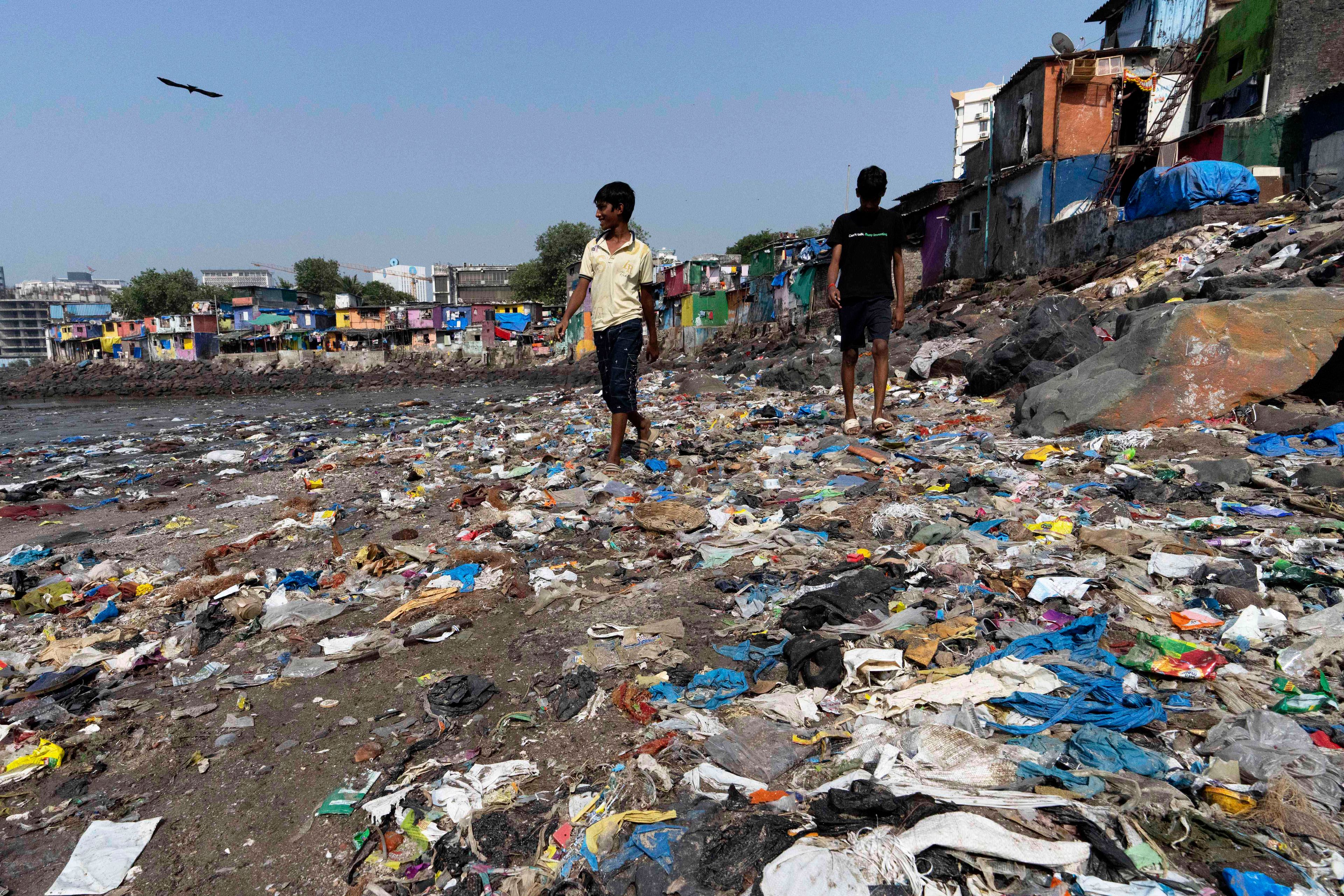 People walk past plastic waste on Badhwar Park beach by the Arabian Sea coast in Mumbai, India, Tuesday, Nov. 26, 2024.(AP Photo/Rajanish Kakade)