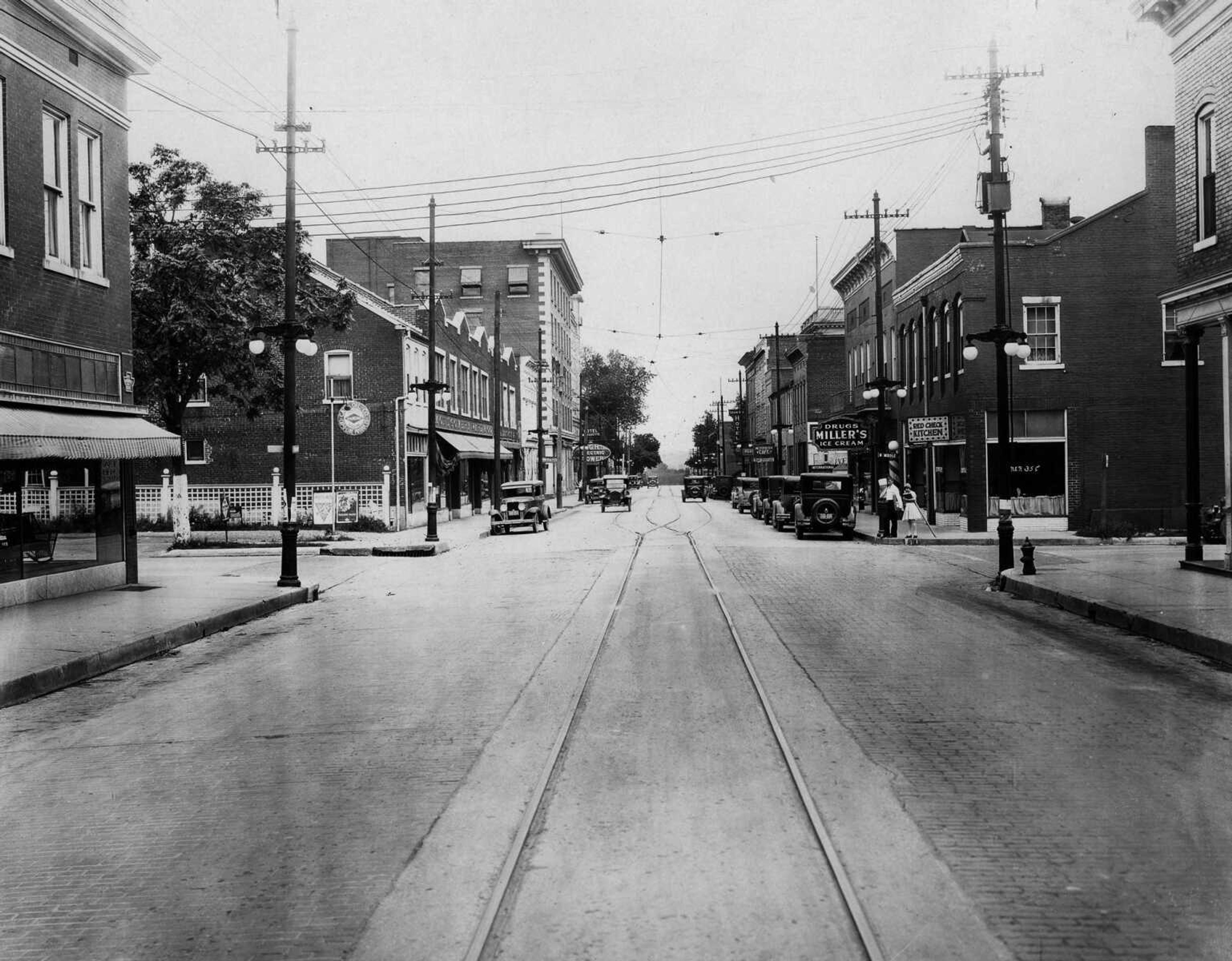 Two school children waited to cross Broadway at the Middle Street intersection in 1929. Behind them, the Red Check Kitchen provided dinners for 35 cents. The I. Ben Miller's drug store was east of the kitchen, while across the street was the Montgomery Ward Co. store. (Published Oct. 3, 1929, Missourian's 25th anniversary edition)