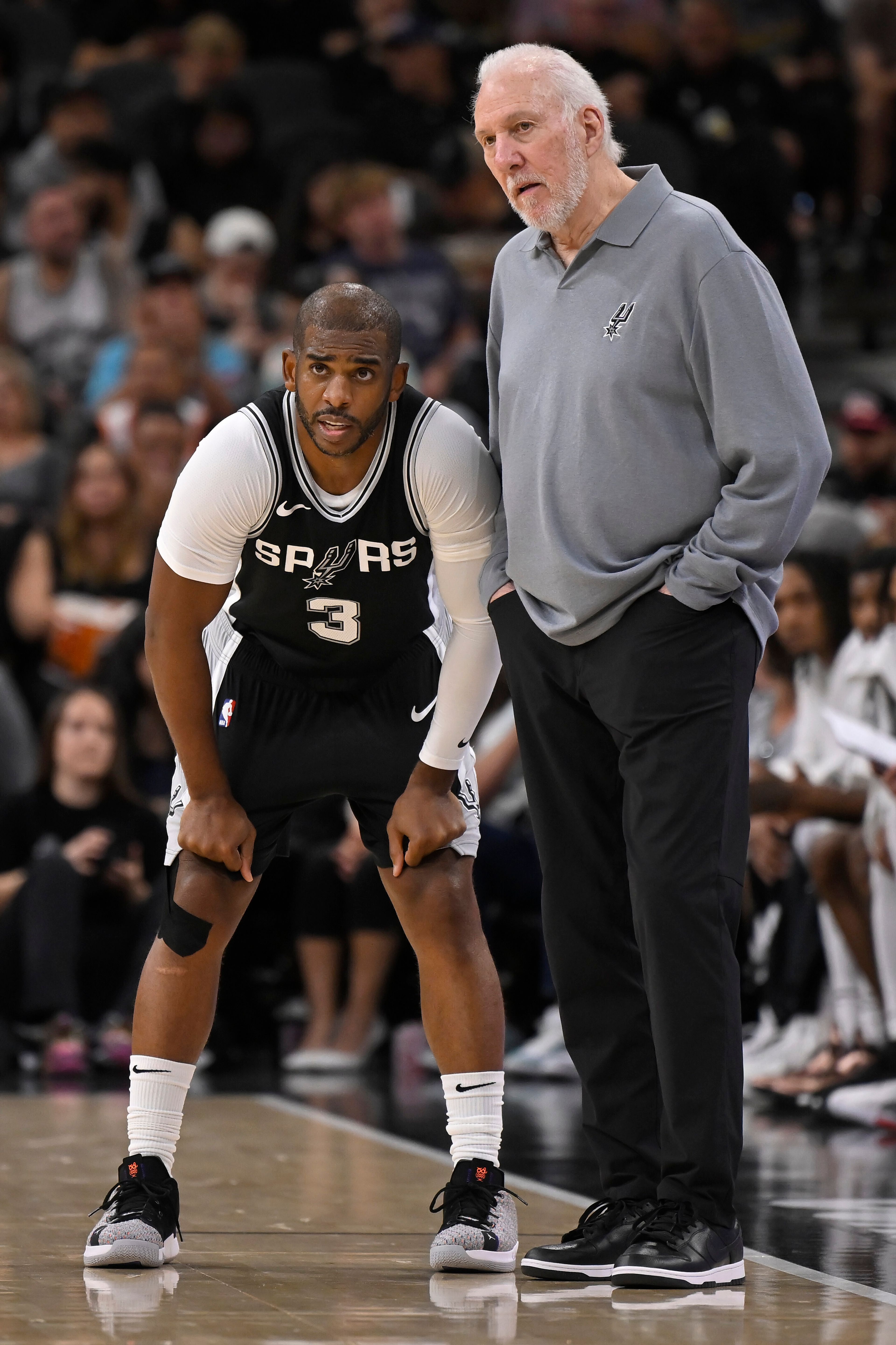 San Antonio Spurs head coach Gregg Popovich, right, speaks with Spurs guard Chris Paul, left, during the first half of an NBA basketball game against the Houston Rockets, Monday, Oct. 28, 2024, in San Antonio. (AP Photo/Darren Abate)