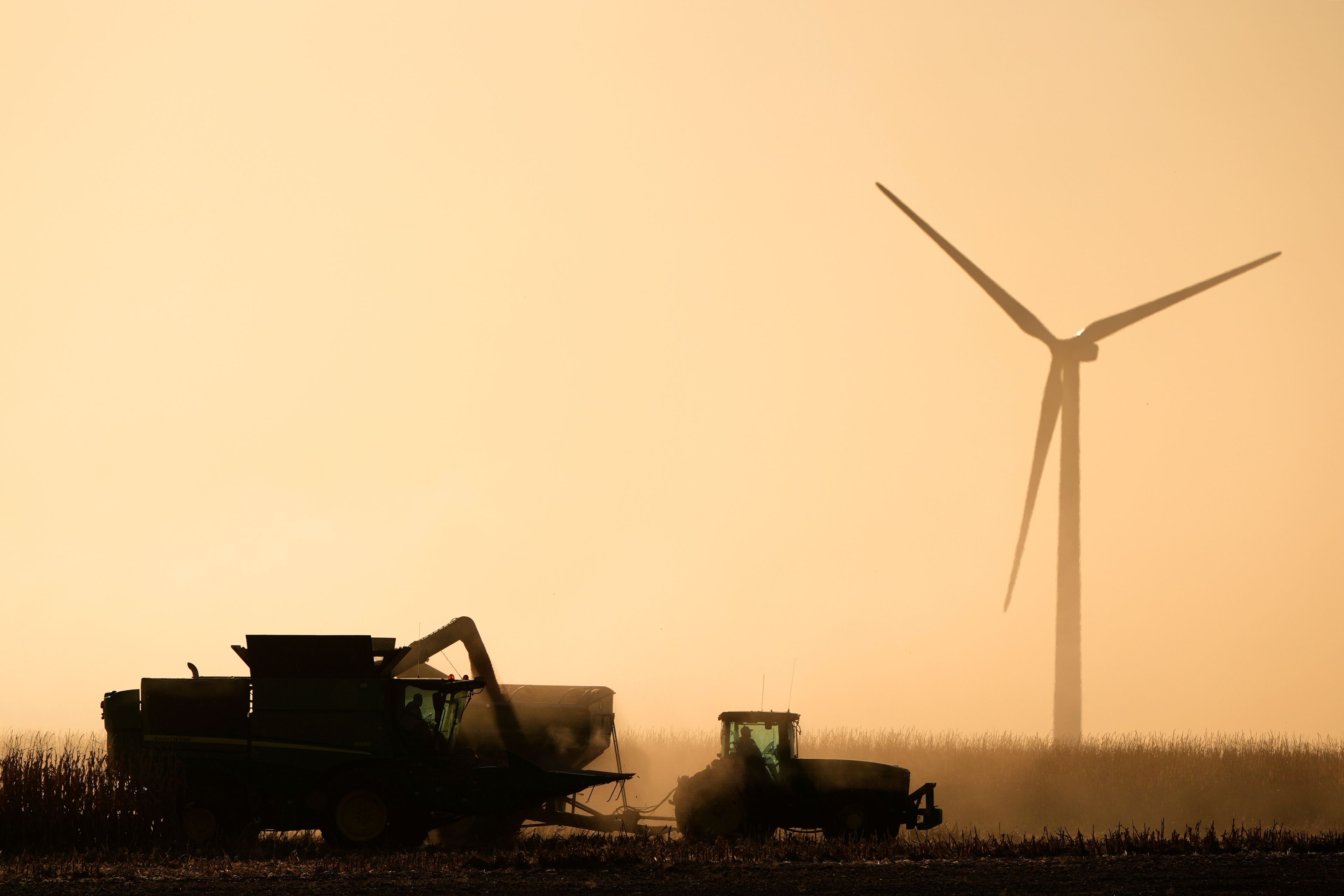 A wind turbine towers above a farmer as he works a field at the Spearville Wind Farm, Sunday, Sept. 29, 2024, near Spearville, Kan. (AP Photo/Charlie Riedel)