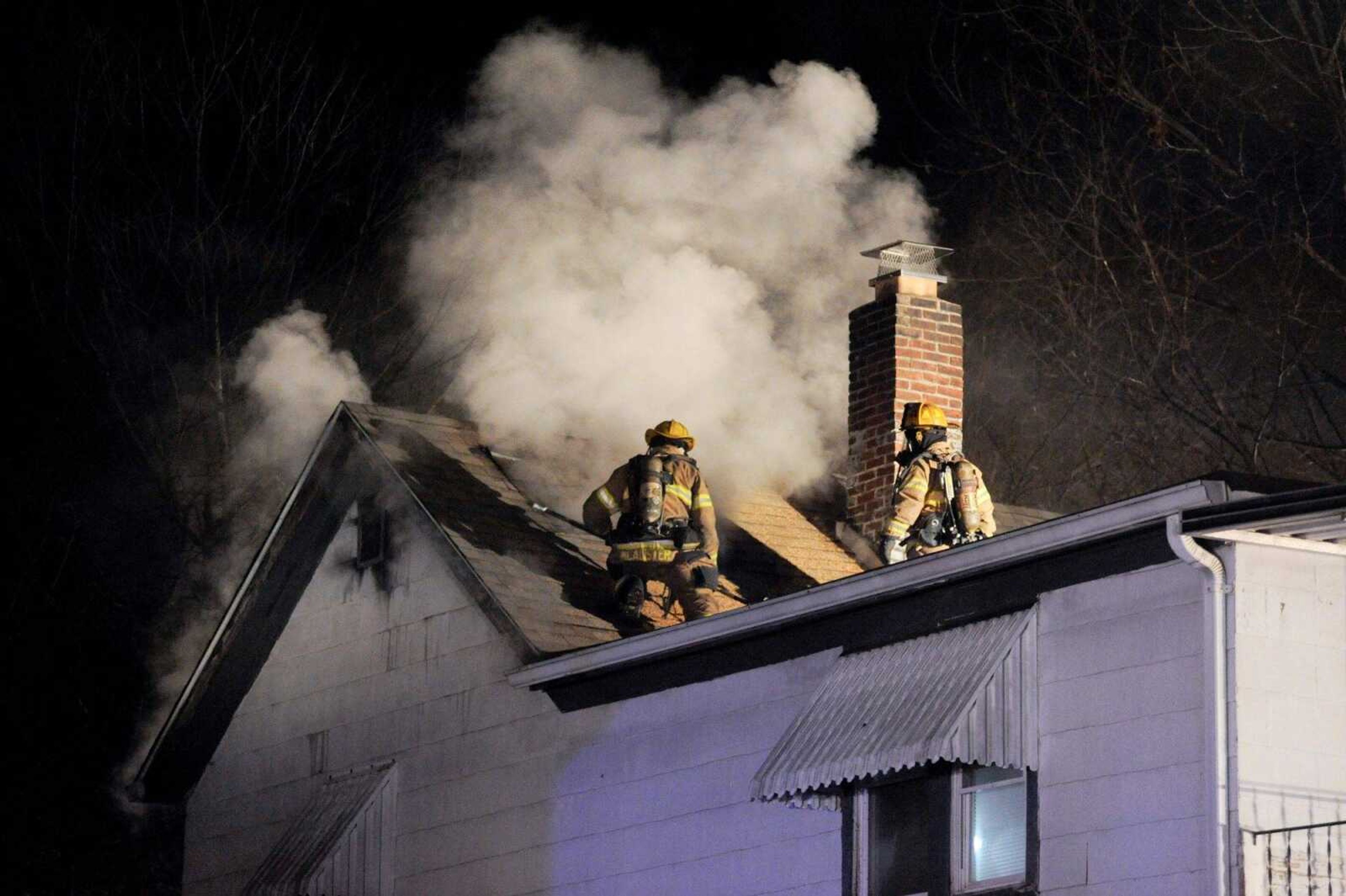 Members of the Cape Girardeau Fire Department cut holes in the roof of a two-story house to fight an attic fire that broke out Wednesday night at the corner of 803 Themis St. (Glenn Landberg)