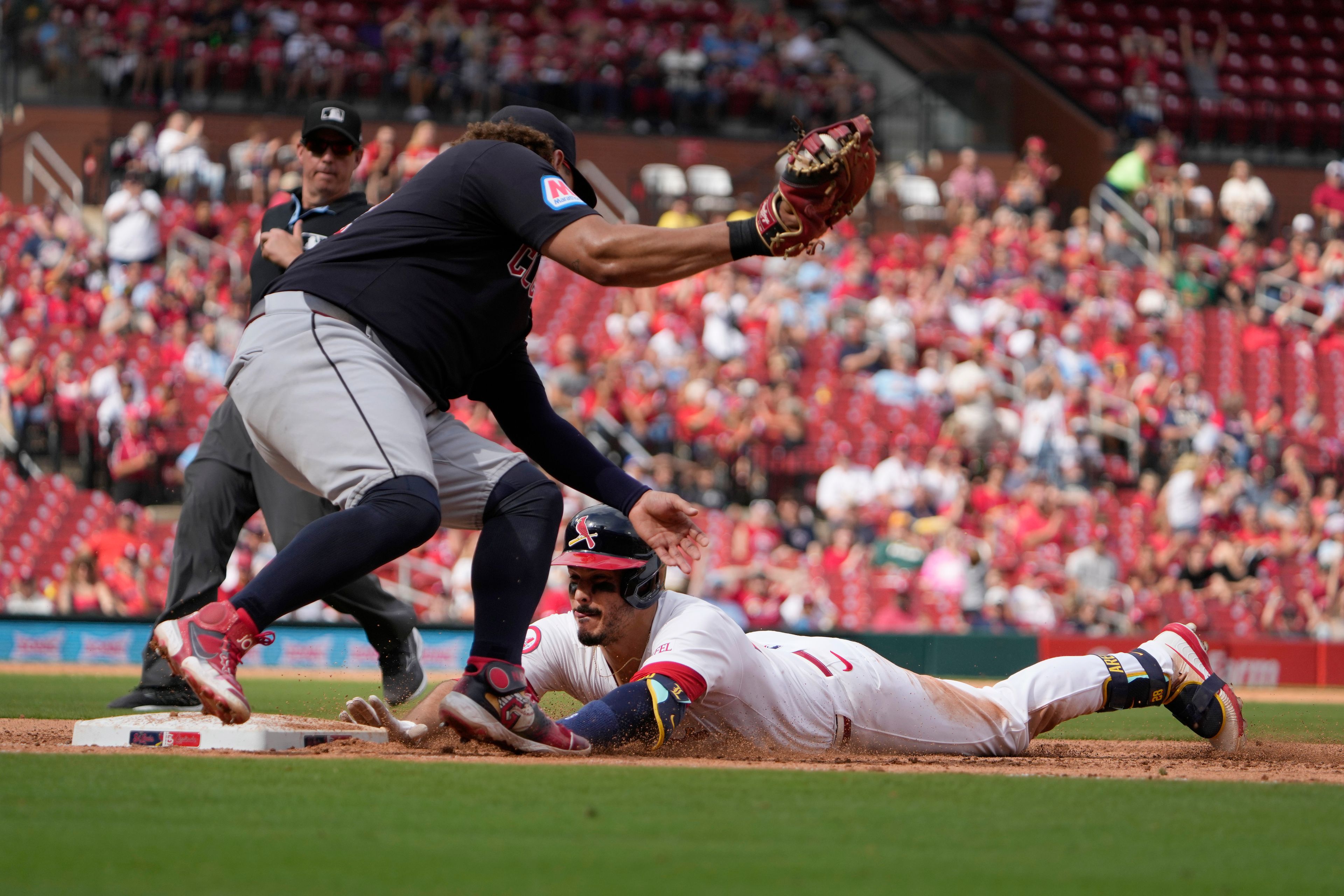 St. Louis Cardinals' Nolan Arenado, right, dives back to first ahead of the tag from Cleveland Guardians first baseman Josh Naylor after hitting an RBI single during the sixth inning of a baseball game Sunday, Sept. 22, 2024, in St. Louis. (AP Photo/Jeff Roberson)