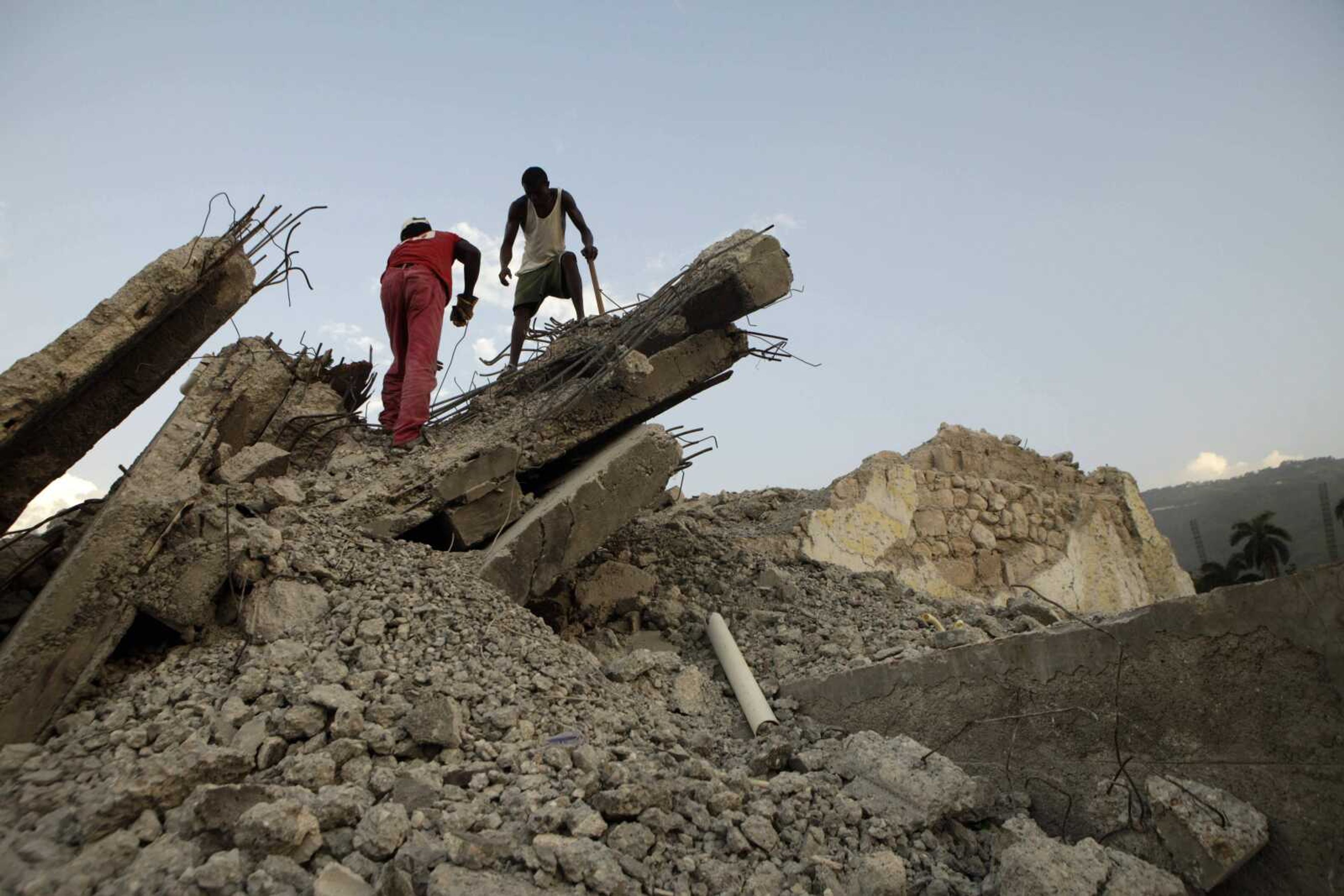 Two men remove rubble Aug. 25 from a building in Port-au-Prince, Haiti. By some estimates, only 2 percent of the earthquake debris in Port-au-Prince has been cleared, for reasons ranging from lack of equipment and money to an abysmal property records system. Meanwhile, most Haitians just live and work around the piles. (Arnulfo Franco ~ Associated Press)