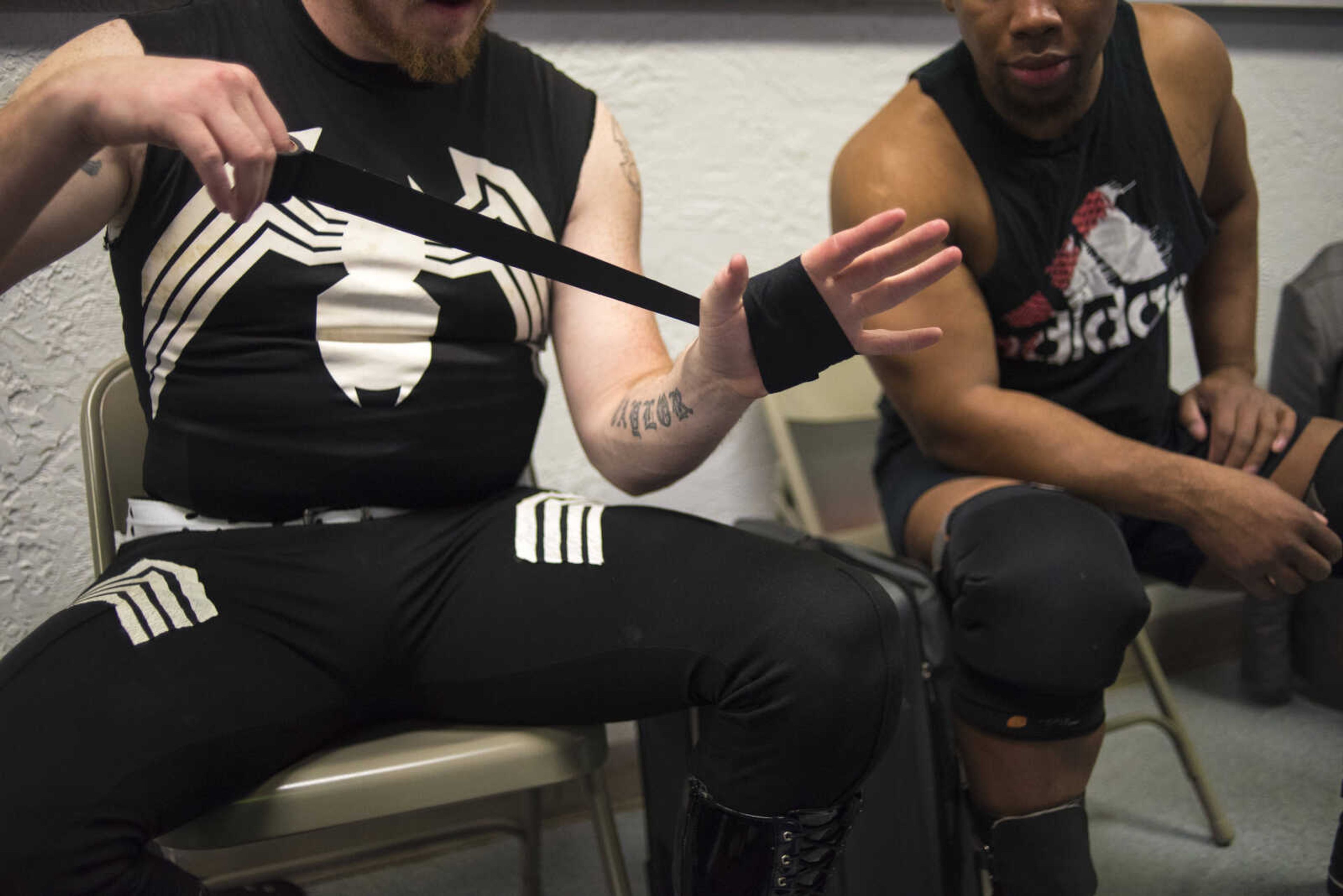 Brandon Barbwire, left, tapes his hand while Hollis Giroux, right, sits next to him during the Cape Championship Wrestling match Saturday, Jan. 28, 2017 at the Arena Building in Cape Girardeau.