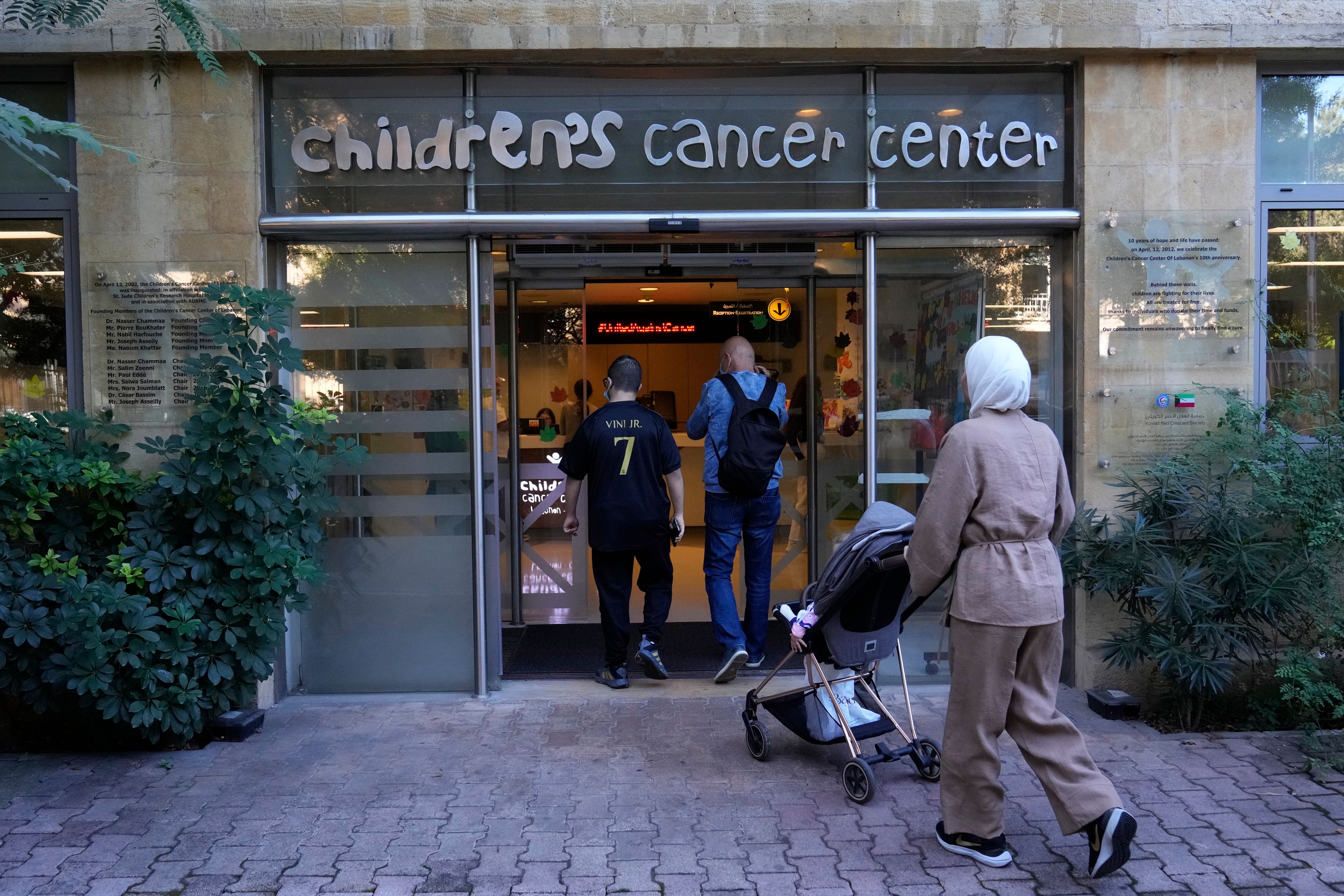 Patents with their child enter the Children's Cancer Center of Lebanon to receive their treatments, in Beirut, Lebanon, Friday, Nov. 15, 2024. (AP Photo/Hussein Malla)