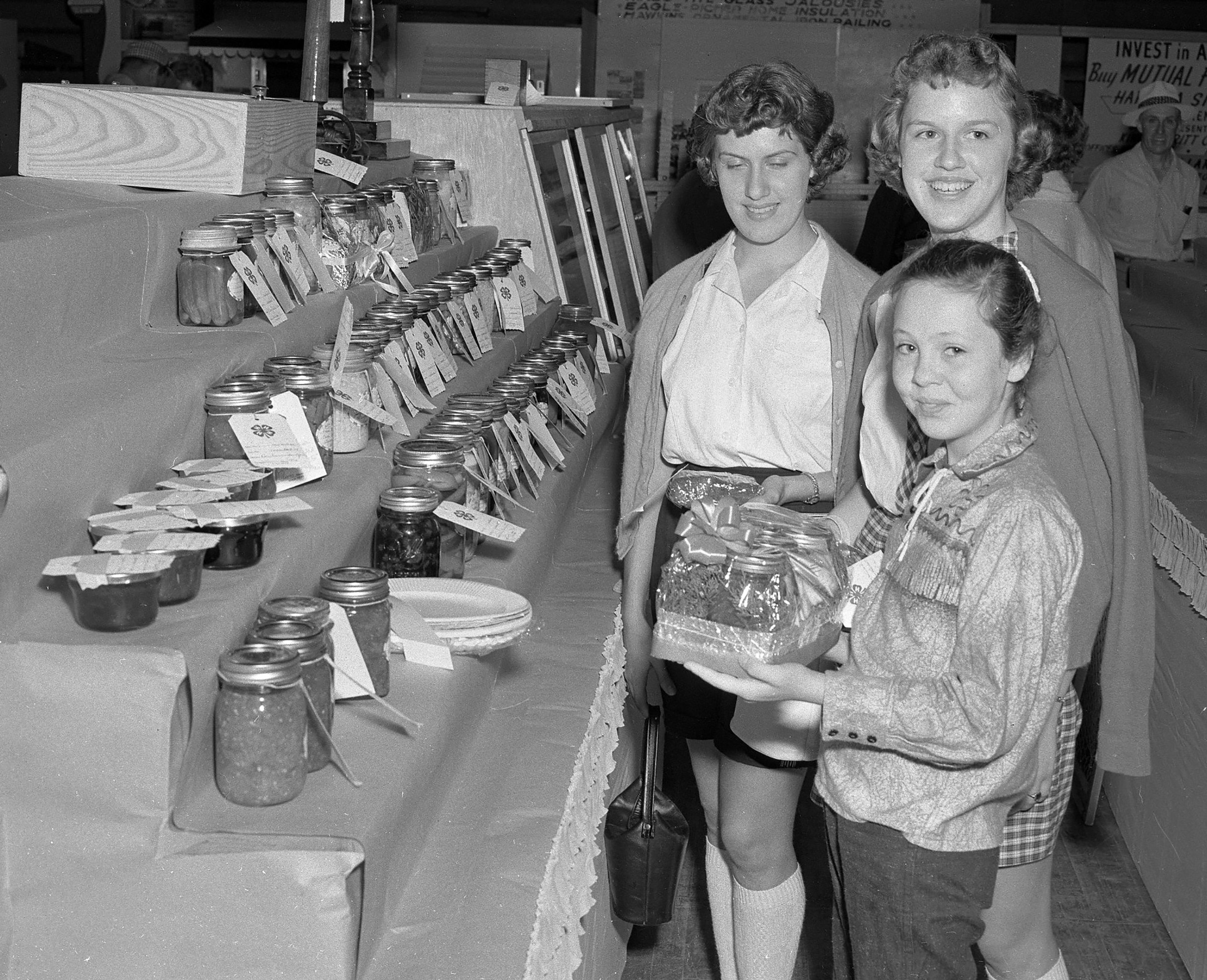 These 4-H Club girls look over some of the items displayed at the SEMO District Fair in September 1957. At the back are Barbara and Noretta Phillips, sisters, from the Oak Grove Club, and Linda Revelle of Oak Valley Club.