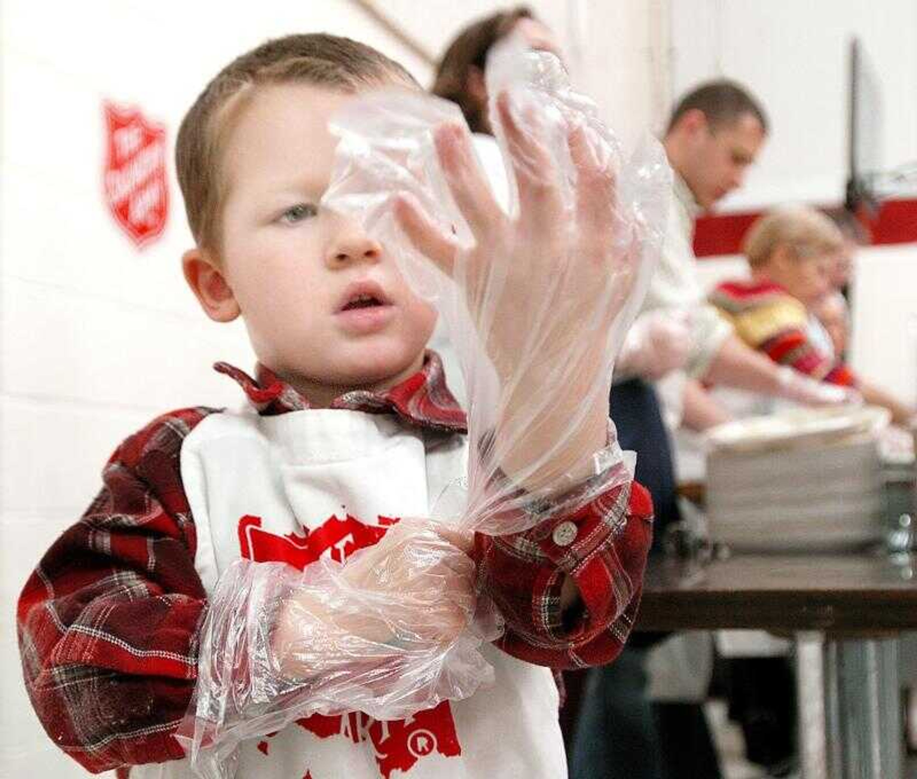 Tanner Smith, 5, put on large gloves before helping with the annual Salvation Army Thanksgiving meal in Cape Girardeau on Thursday. More than 300 meals were served, and another 200 were delivered. (Photos by Diane L. Wilson)