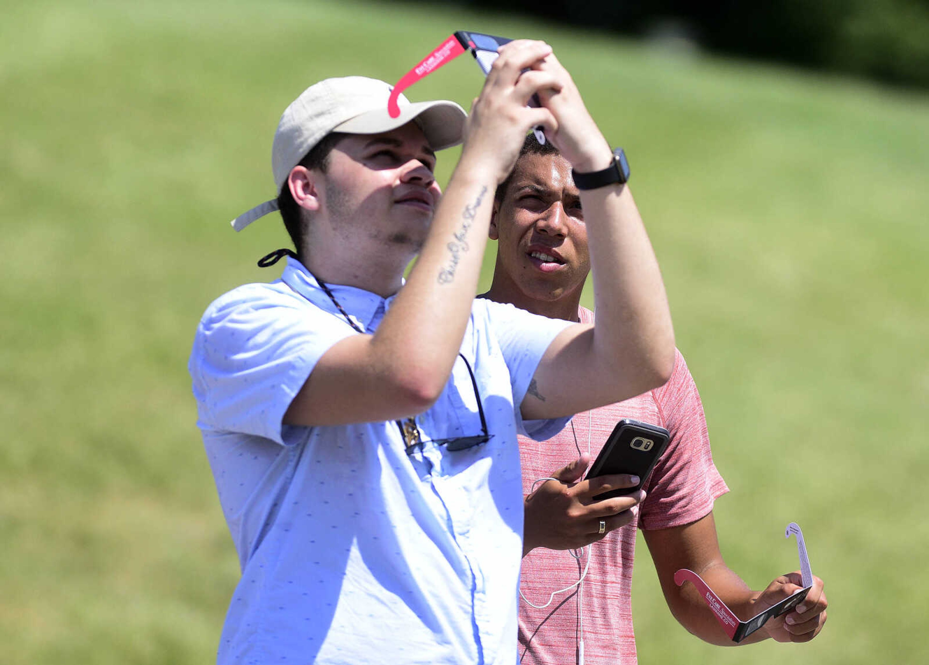 Trace Arnold, right, watches as Javier Easkles takes a photo on his smart phone through his eclipse glasses on Monday, Aug. 21, 2017, at the River Campus in Cape Girardeau.