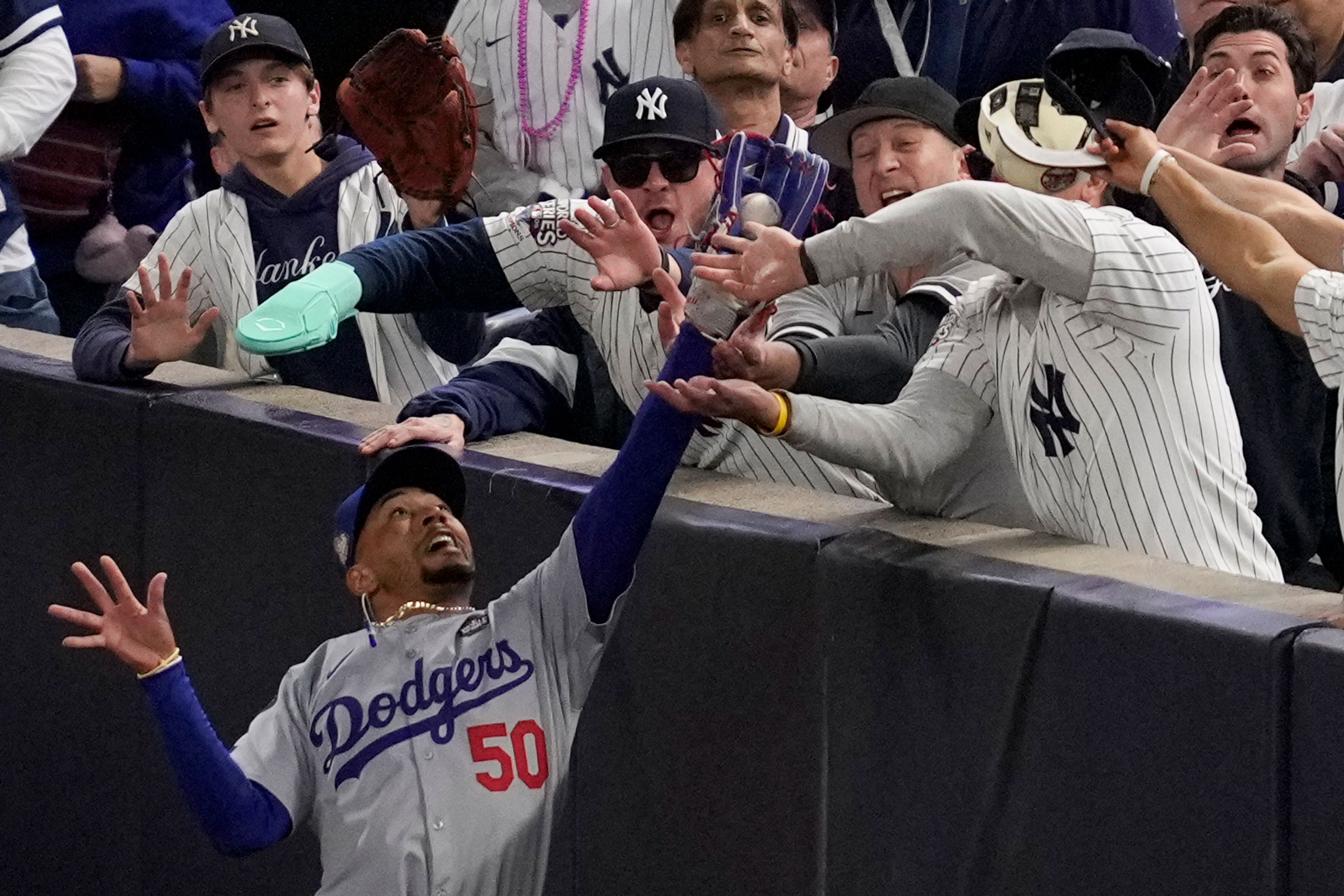 Fans interfere with a foul ball caught by Los Angeles Dodgers right fielder Mookie Betts during the first inning in Game 4 of the baseball World Series against the New York Yankees, on Oct. 29, 2024, in New York. (AP Photo/Ashley Landis)