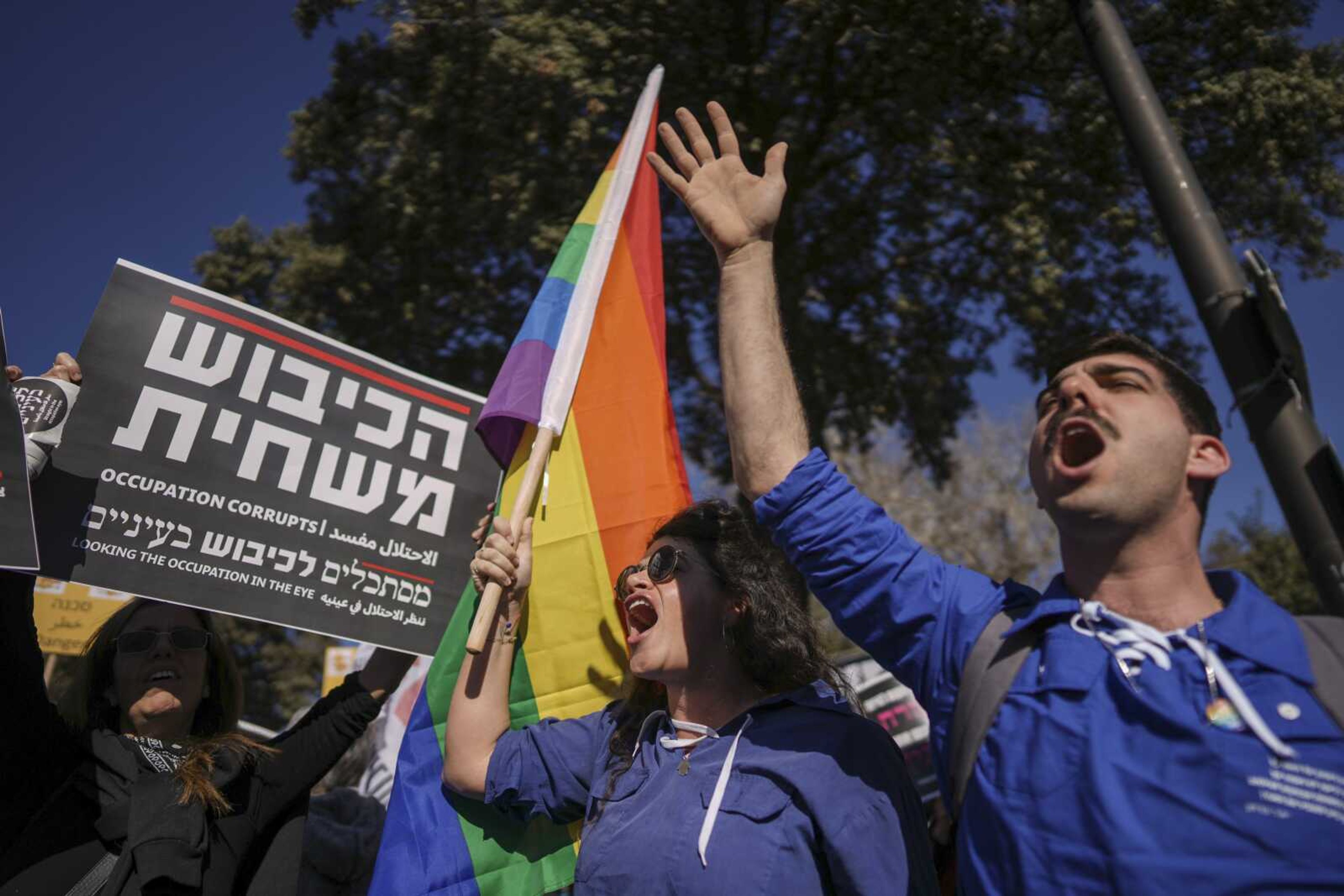 Protesters waving a rainbow flag, often symbolizing the LGBTQ+ community, and a sign that reads in Hebrew "the occupation corrupts" protest Benjamin Netanyahu's new government in front of Israel's Parliament in Jerusalem, Thursday.