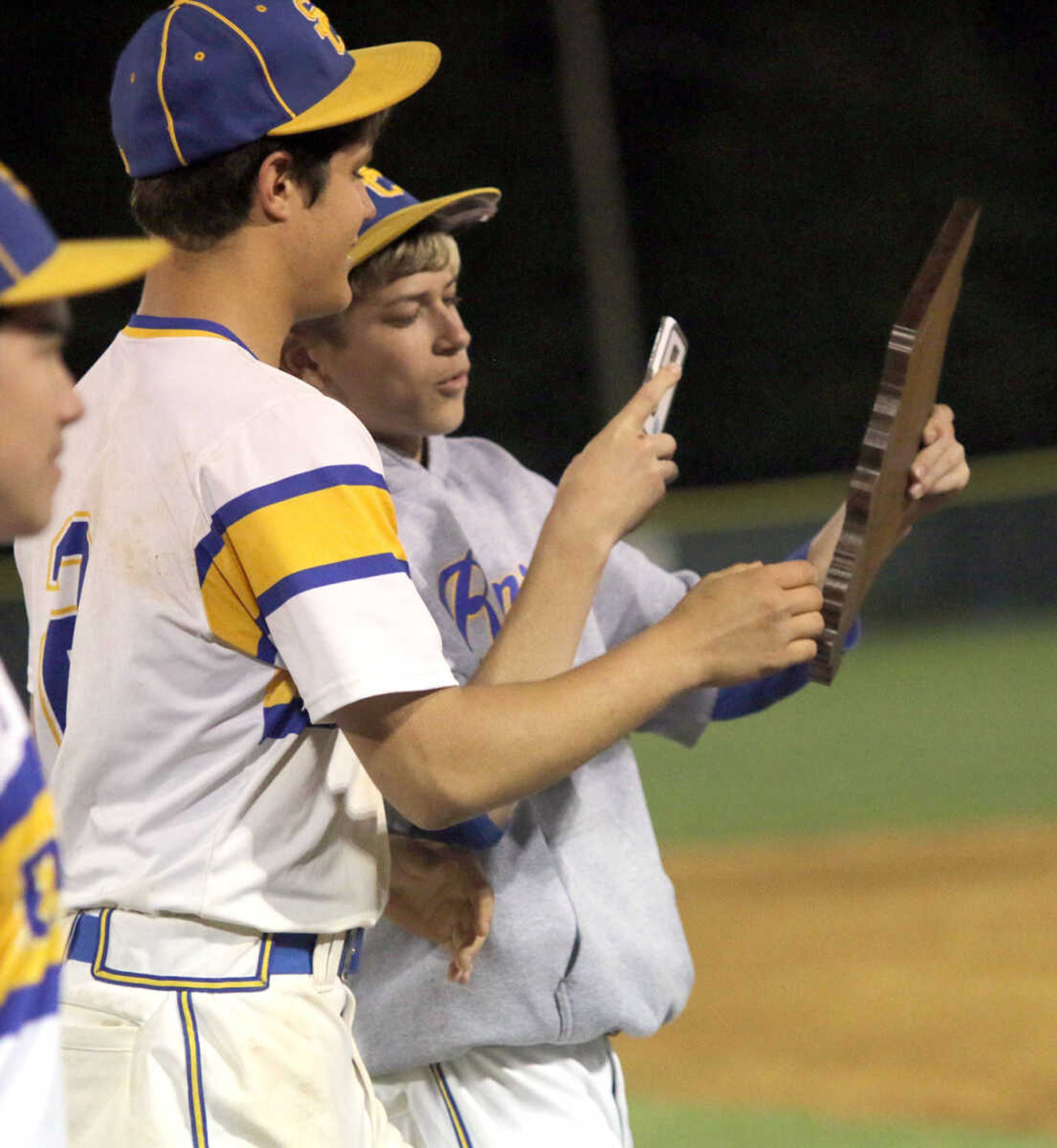 A member of Scott City's baseball team takes a picture of the Class 3, District 2 plaque with his cell phone Wednesday following the Class 3, District 2 championship game at VFW Memorial Stadium in Sikeston, Mo. Scott City won 9-4.