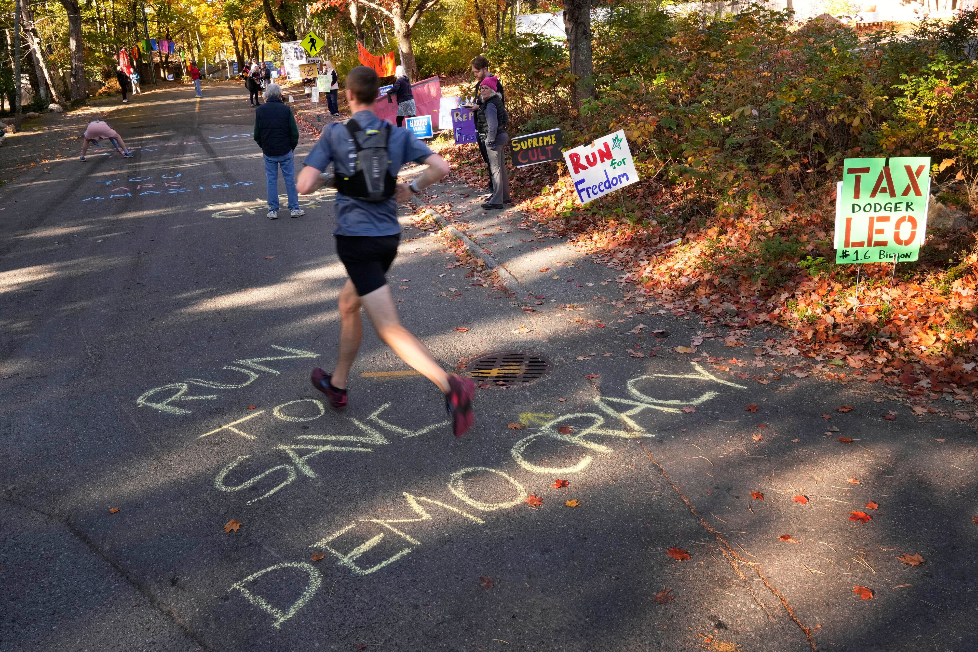 Messages are written in chalk during a protest in front of the home of Leonard Leo during the Mount Desert Island Marathon, Sunday, Oct. 20, 2024, in Northeast Harbor, Maine. (AP Photo/Robert F. Bukaty)