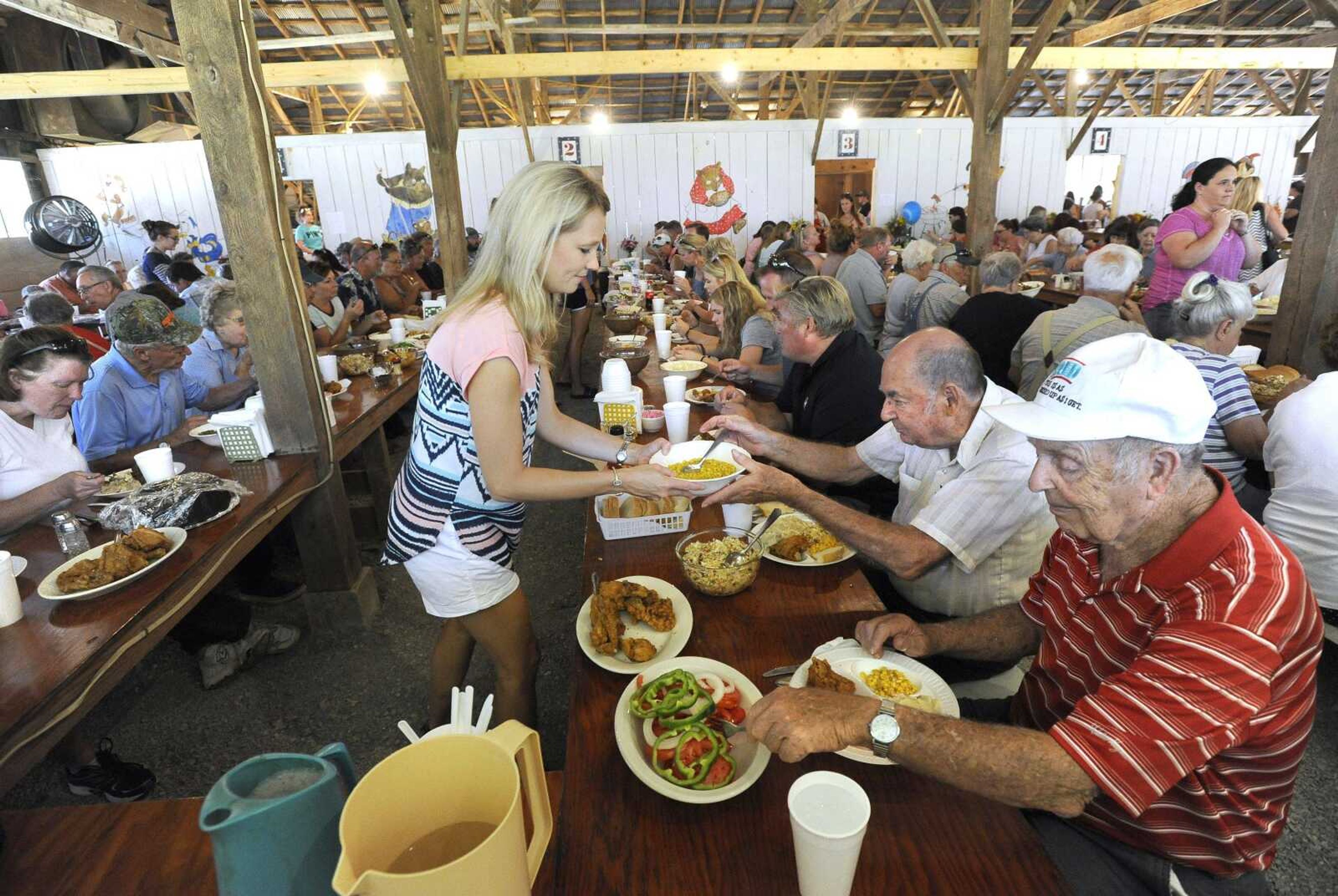 Stacey Van de Ven serves her table of guests including Vernon Homan, right, and John Brandel on Saturday at the St. John's Church Picnic in Leopold, Missouri.