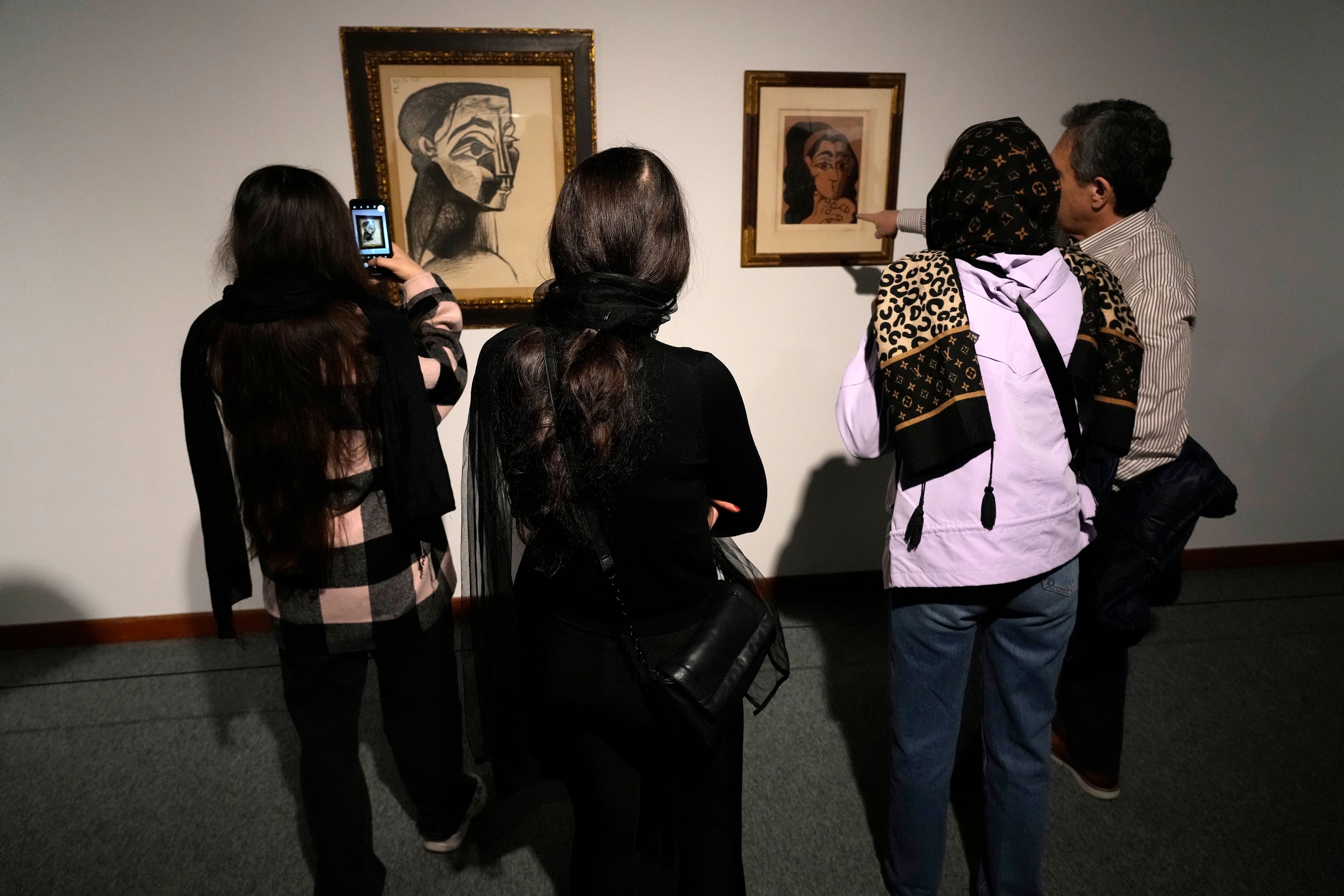 Visitors look at artworks by the Spanish artist Pablo Picasso as one of them takes a snapshot while visiting an exhibition titled Eye to Eye which showcases over 120 works by modern world artists as well as Iranian painters at Tehran Museum of Contemporary Art, in Tehran, Thursday, Nov. 21, 2024. (AP Photo/Vahid Salemi)