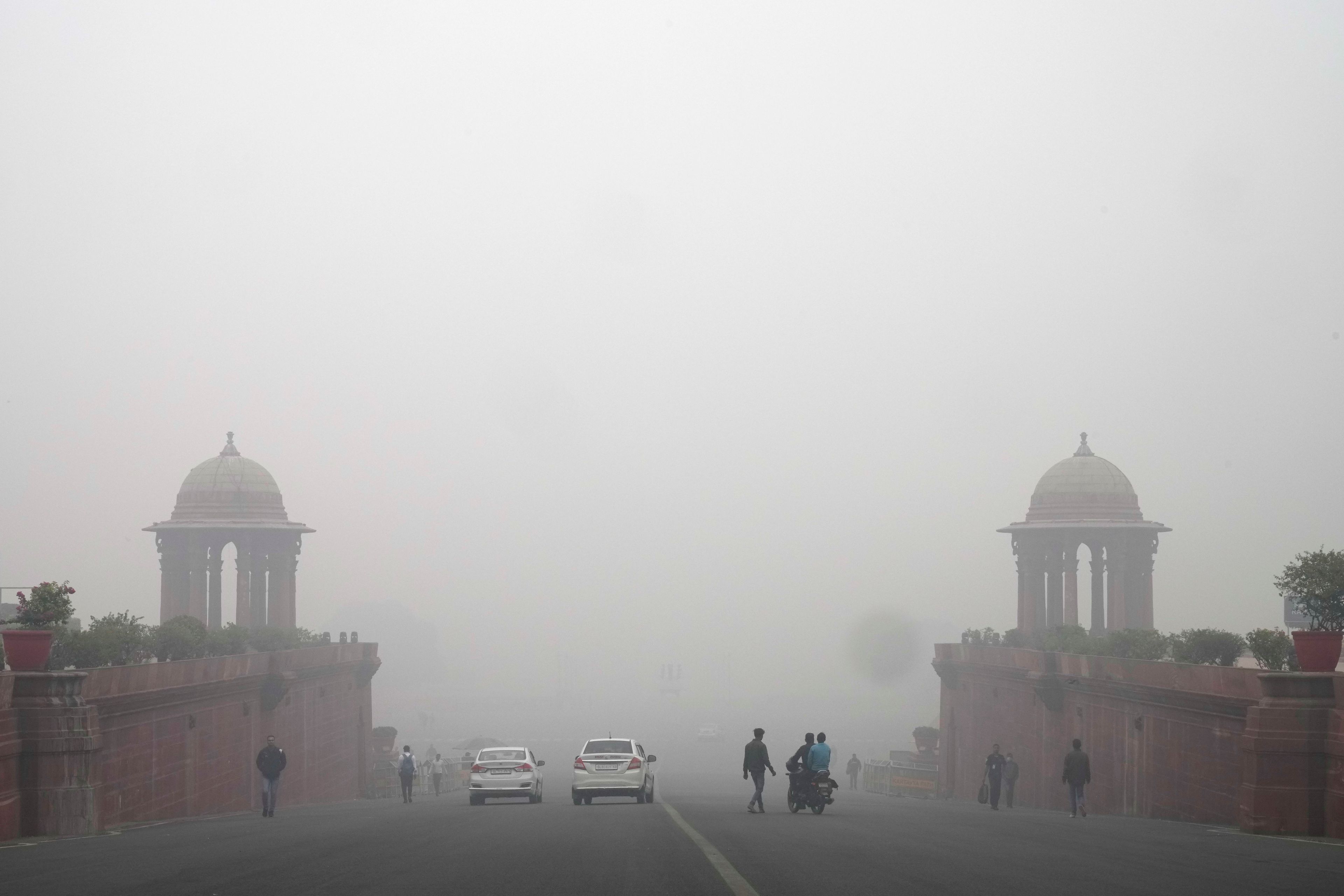 Office goers walk wearing a face mask amidst a thick layer of smog as air pollution shoots up in New Delhi, India, Monday, Nov. 18, 2024. (AP Photo/Manish Swarup)