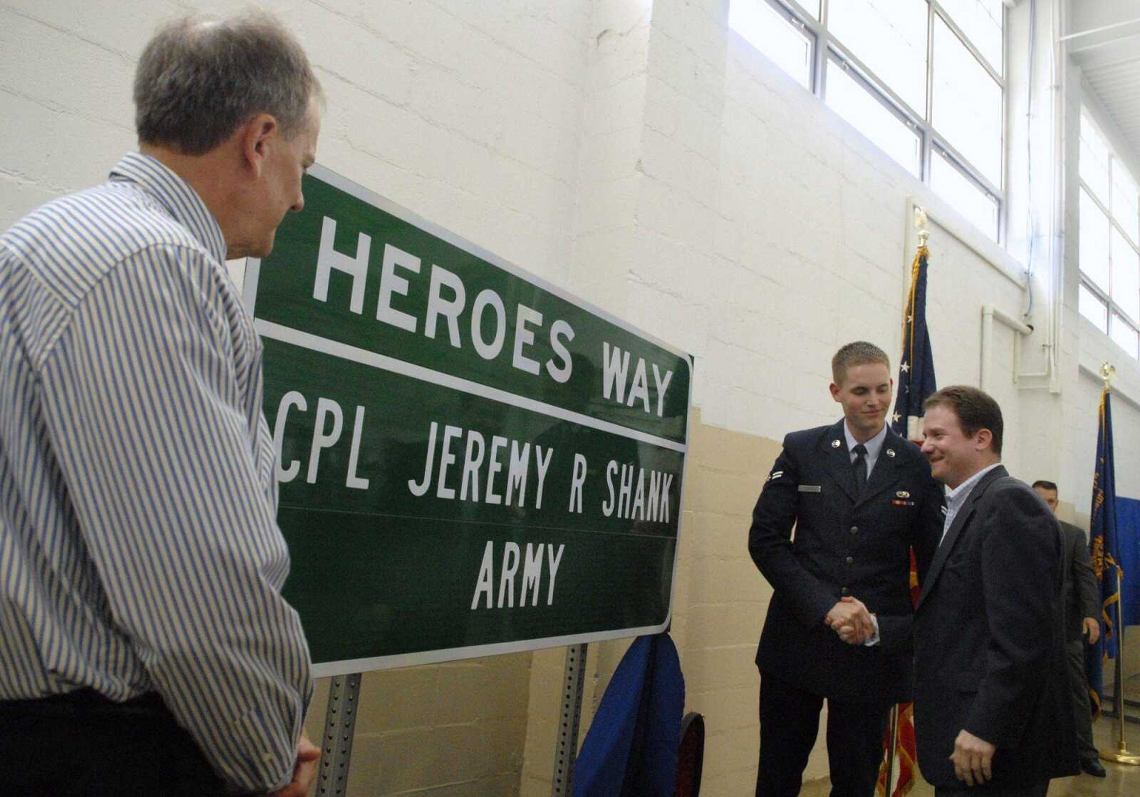 Nathan Shank, of the U.S. Air Force, shakes hands with Missouri Senator Jason Crowell after he and father Jim Shank, left, unveiled a sign that will dedicate Interstate 55 Exit 102 in Jackson, Mo., to Nathan's brother, Corporal Jeremy Shank, who was killed while serving in Iraq in 2006. A Heroes Way Interchange Dedication Ceremony was held at the National Guard Armory in Jackson on Saturday, May 22, 2010, to honor Shank and three other local soldiers killed in Iraq or Afghanistan. (KRISTIN EBERTS)