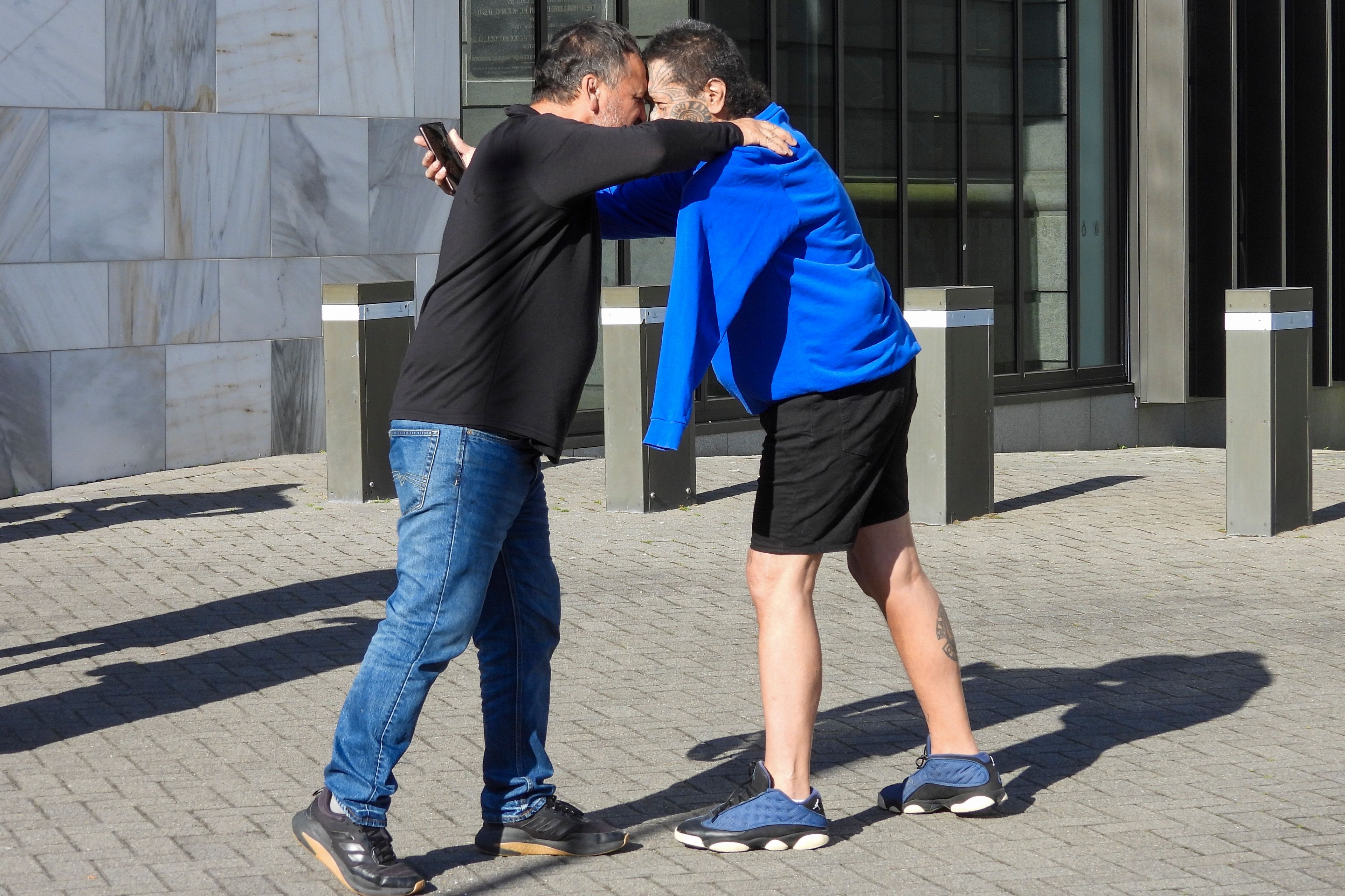 Two men great each other with a hongi, a Maori greeting, as they arrive at Parliament House in Wellington, New Zealand, ahead of the apology to the survivors of abuse in state, faith-based and foster care over a period of seven decades, Tuesday, Nov. 12, 2024. (AP Photo/Charlotte Graham-McLay )