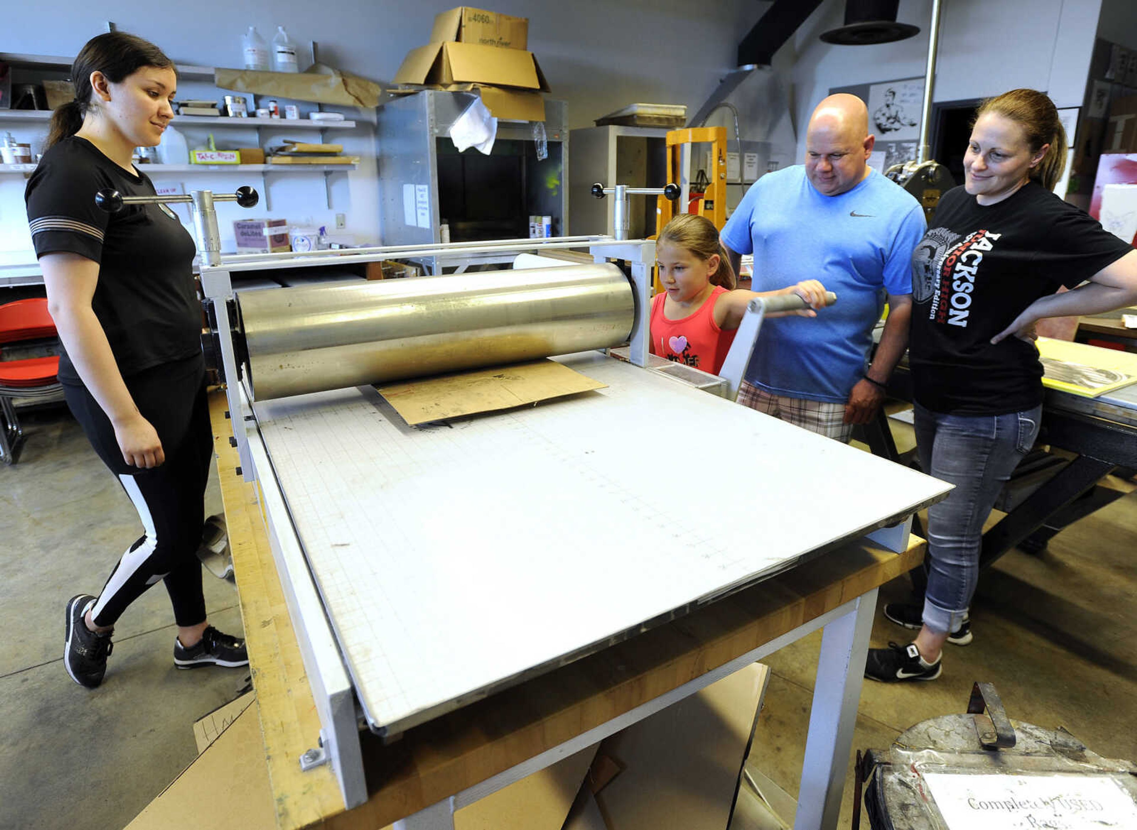 FRED LYNCH ~ flynch@semissourian.com
Leslie Mata, left, watches as Kerrigan Murphy cranks out a print with her parents, Delbert and Laura Murphy, Saturday, June 16, 2018 at the Summer Arts Festival at the River Campus.