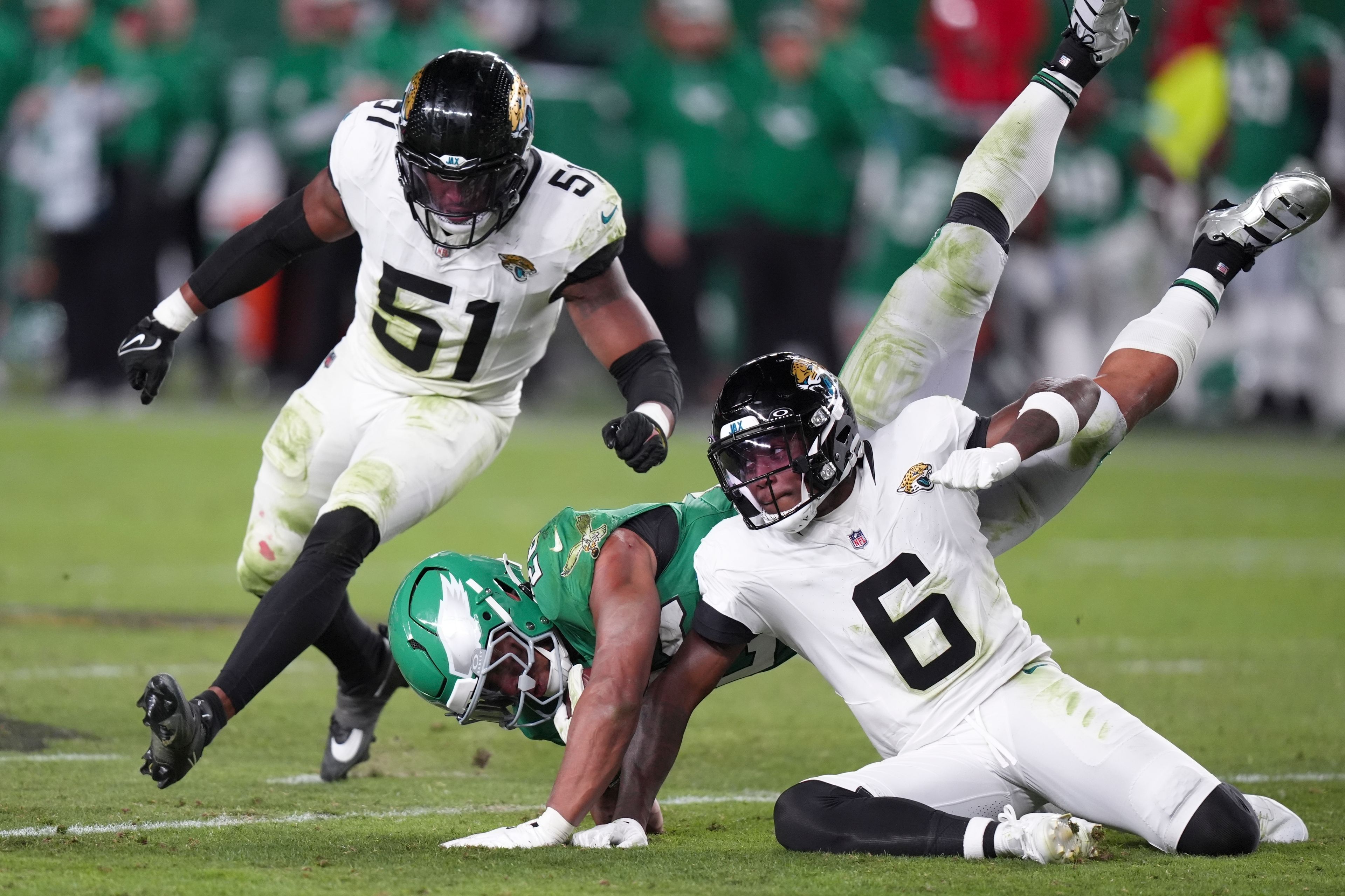 Philadelphia Eagles running back Saquon Barkley (26) falls with the ball after Jacksonville Jaguars safety Darnell Savage (6) upended him near Jaguars linebacker Ventrell Miller (51) during the second half of an NFL football game Sunday, Nov. 3, 2024, in Philadelphia. (AP Photo/Chris Szagola)