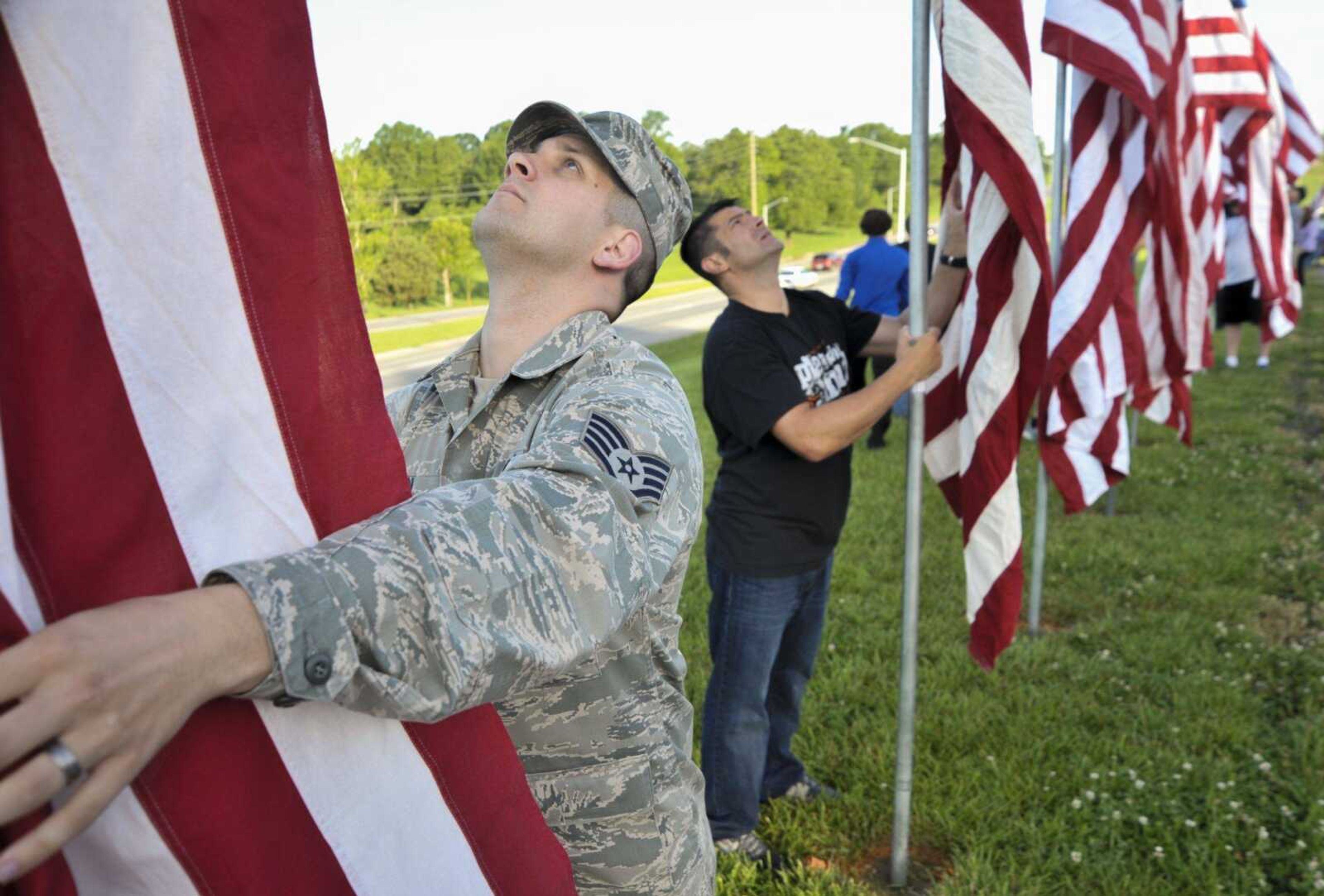 Staff Sgt. Garrett Dixon volunteers to help set up flags in Cape Girardeau County Park North on Monday in Cape Girardeau.