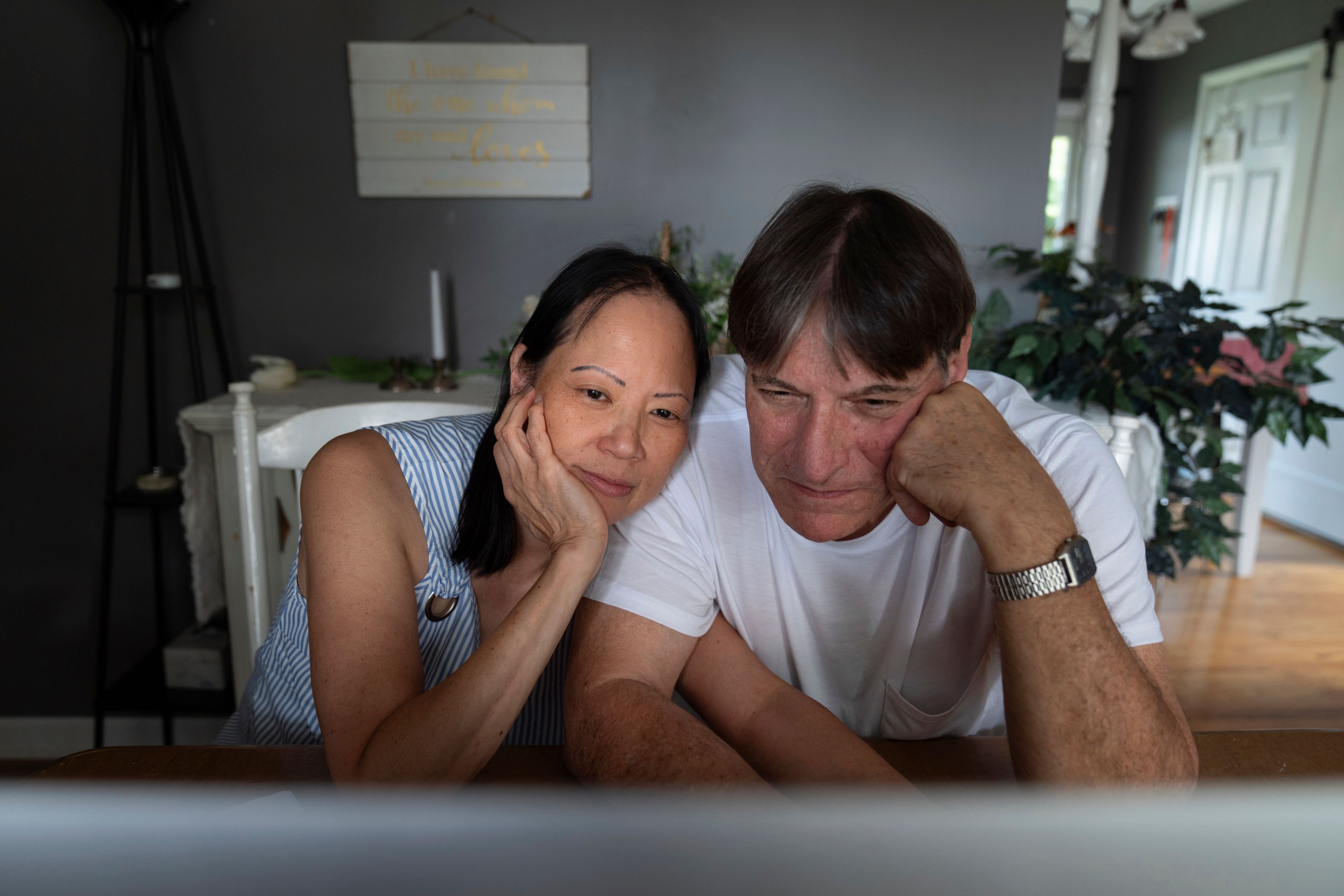 Lesley, left, and Matt Dzik, watch a seminary studies presentation by Lesley's son on a laptop in their home in Champaign, Ill., Friday, Sept. 20, 2024. When they started dating, all it took was the sight of Democratic lawn signs outside Matt's house ahead of the 2020 election to make Lesley question if their relationship could work. (AP Photo/David Goldman)