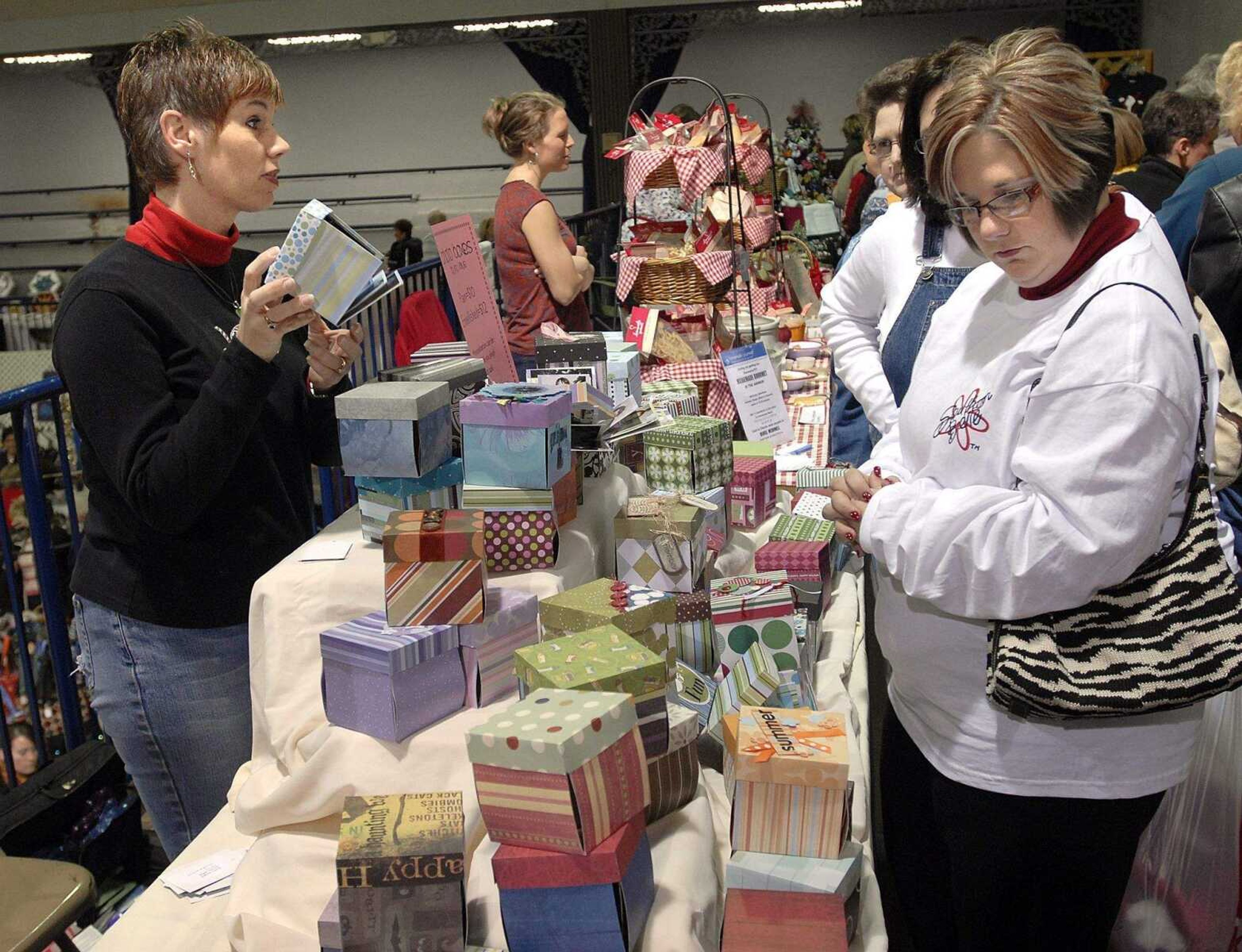 FRED LYNCH ~ flynch@semissourian.com
Joy Kaye Watson, left, of Jackson shows her crafted photo boxes as Beth Hopkins, right, of East Prairie, Mo. considers a purchase at the River Valley Craft Club Christmas Expo Nov. 22 at the Arena Building.