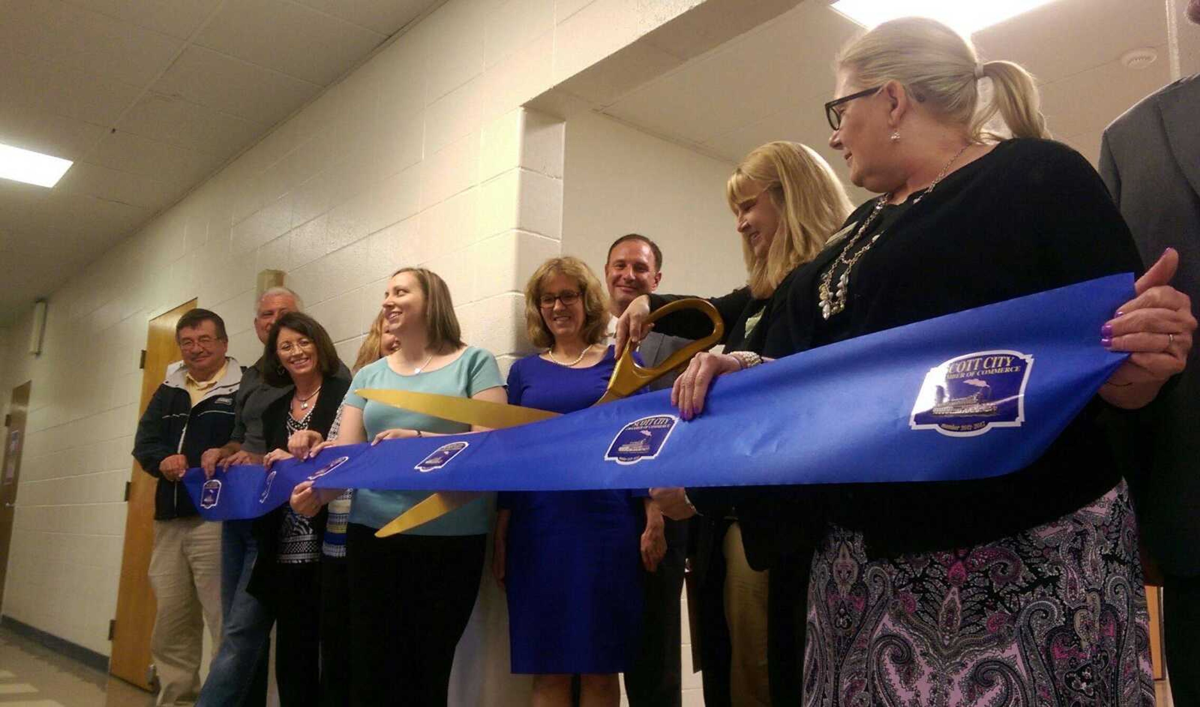 Scott City School District superintendent Diann Ulmer, center, cuts a ribbon to celebrate the grand opening of the district's safe room and visual and performing arts center Wednesday. (Katie Lamb)