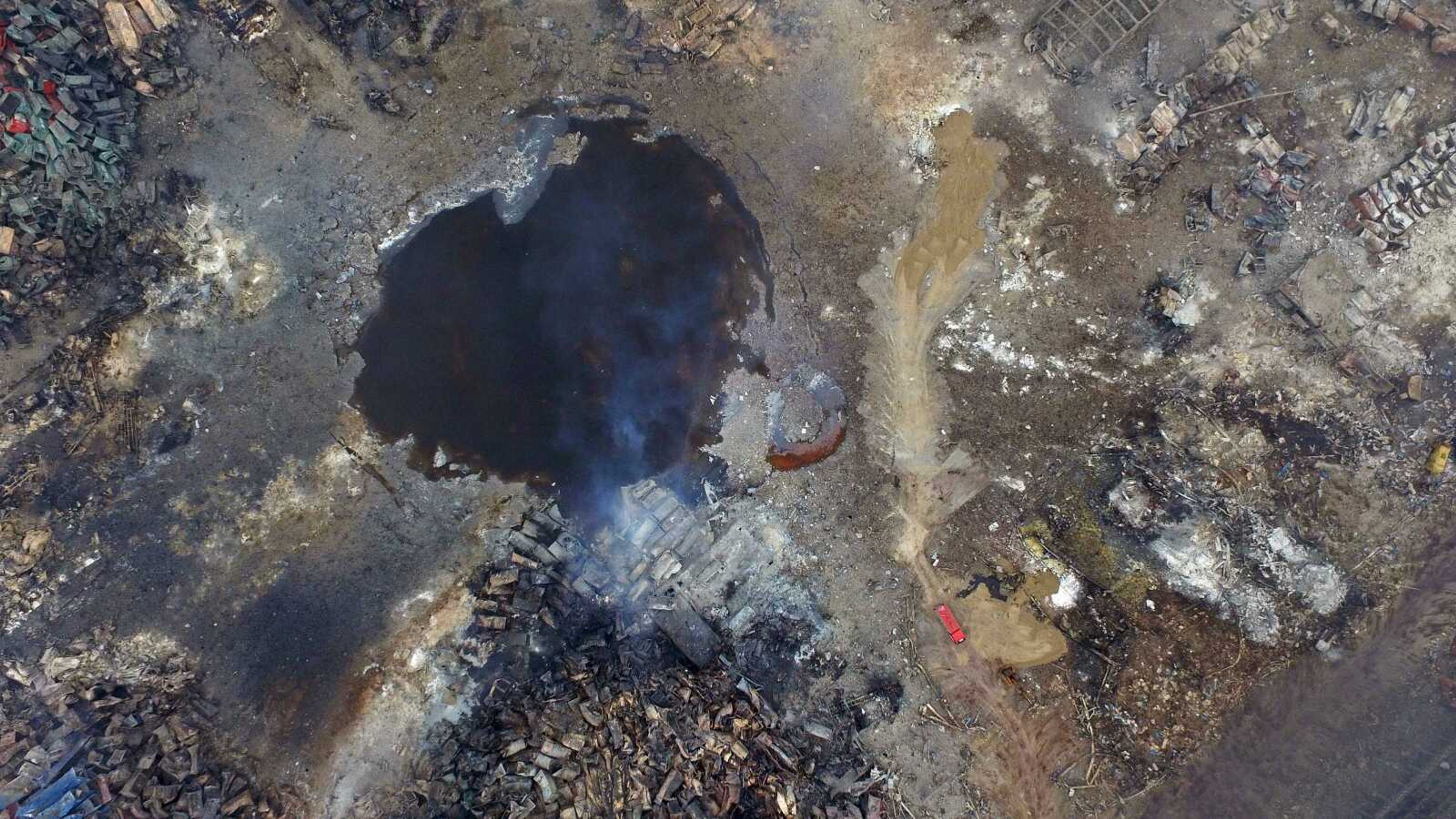 Smoke rises from debris near a crater at the center of a series of explosions in China's Tianjin municipality Saturday as seen from an aerial view. New explosions and fires rocked the Chinese port city Saturday, as one survivor was pulled out and authorities ordered evacuations to clean up chemical contamination more than two days after a fire and a series of blasts set off the disaster. (Chinatopix via AP)