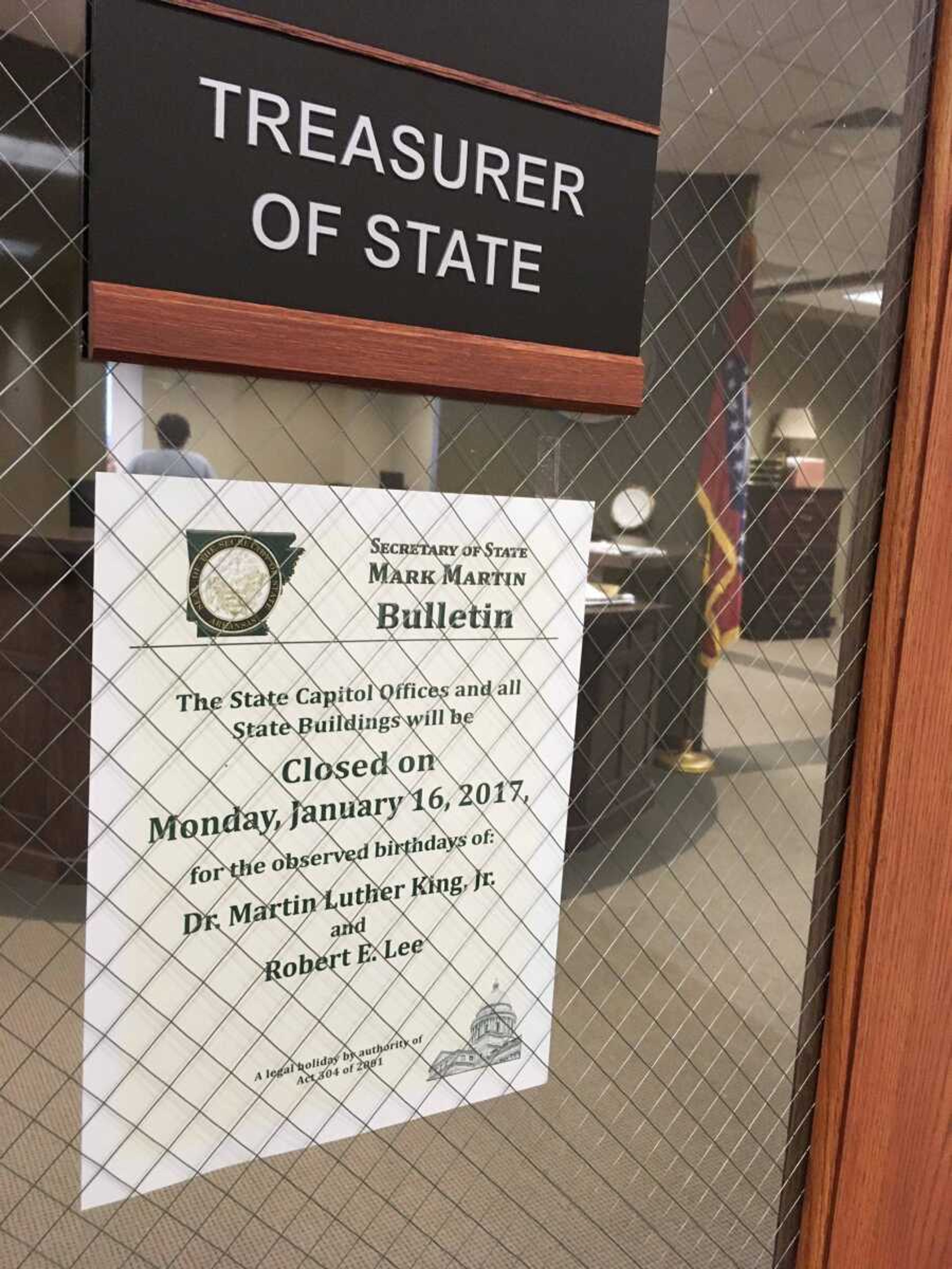 This Friday, Jan. 13, 2017, photo shows a sign on the door of a state treasurer's office in Little Rock, Ark., noting the joint holiday Jan. 16 observing the birthdays of slain civil rights leader Martin Luther King Jr. and Confederate Gen. Robert E. Lee. Gov. Asa Hutchinson is reviving an effort to remove Lee from the holiday. But he faces resistance from opponents who complain the move belittles the state's Confederate heritage and from black lawmakers worried about a plan to set aside another day to honor Lee. (AP Photo/Kelly Kissel)