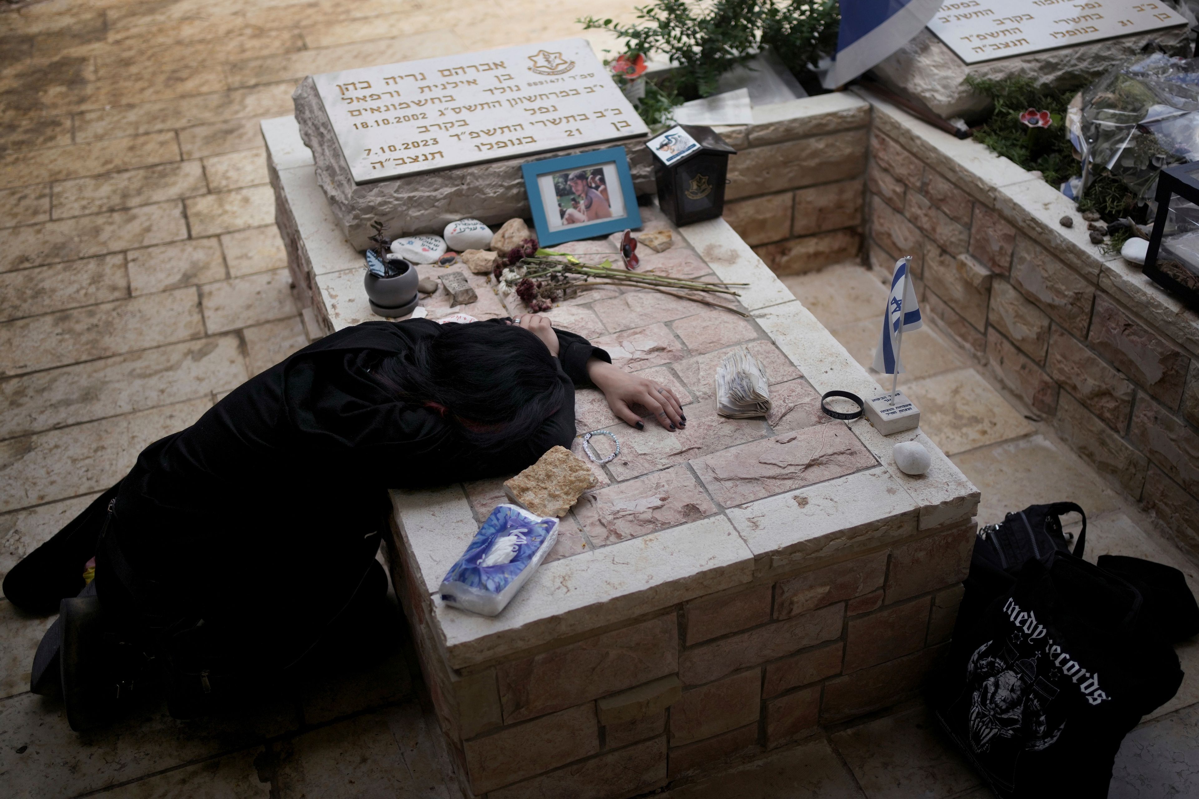 Sara Chen weeps over the grave of her longtime friend, Staff Sgt. Avraham Nerya Cohen, who was killed in action on Oct. 7, 2023, as Israel marks the first anniversary of the Hamas attack on Israel, at the Mount Herzl military cemetery in Jerusalem on Oct. 7, 2024. (AP Photo/Maya Alleruzzo)