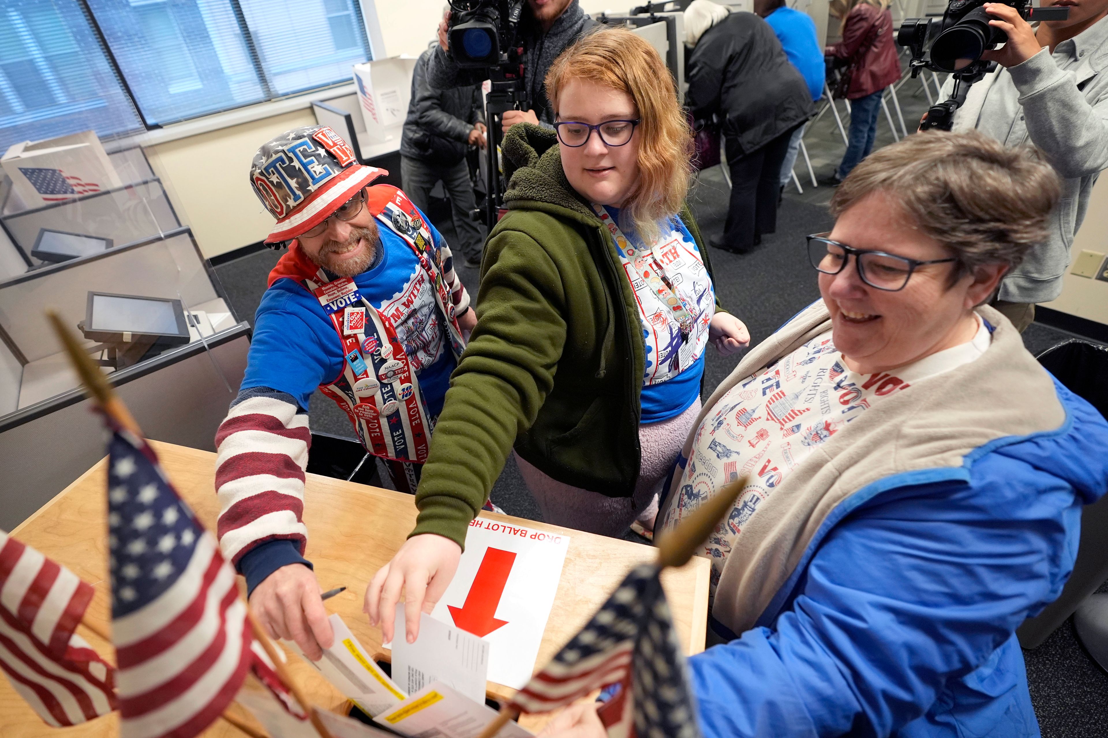 John Olsen, from left, his daughter Alice and his wife Ruby, of Ankeny, Iowa, cast their ballots during early voting at the Polk County Election Office, Wednesday, Oct. 16, 2024, in Des Moines, Iowa. (AP Photo/Charlie Neibergall)