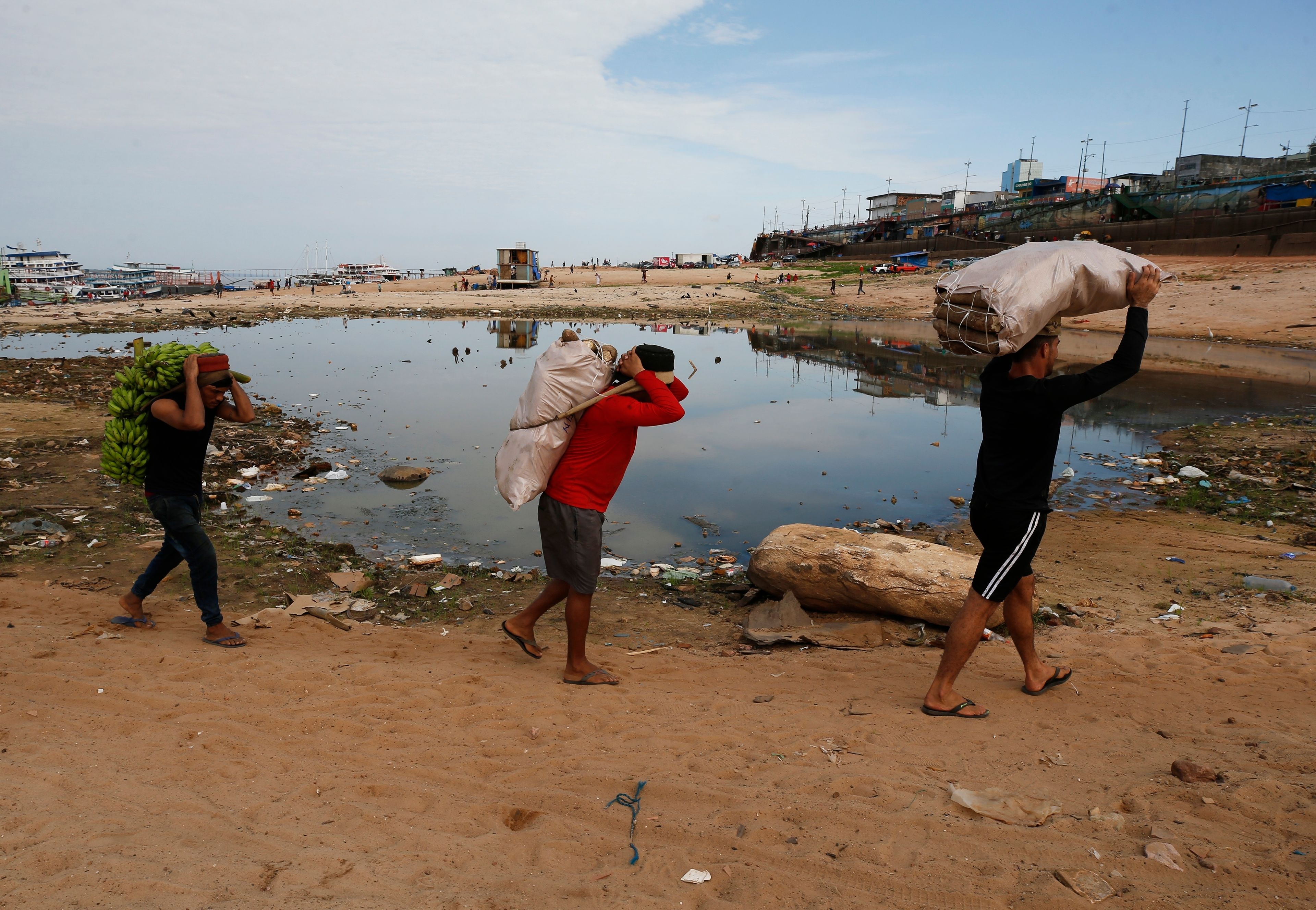 FILE - Porters carry goods brought by boat across a dry area of the Negro River at the port in Manaus, Amazonas state, Brazil, Oct. 4, 2024, amid a severe drought. (AP Photo/Edmar Barros, File)