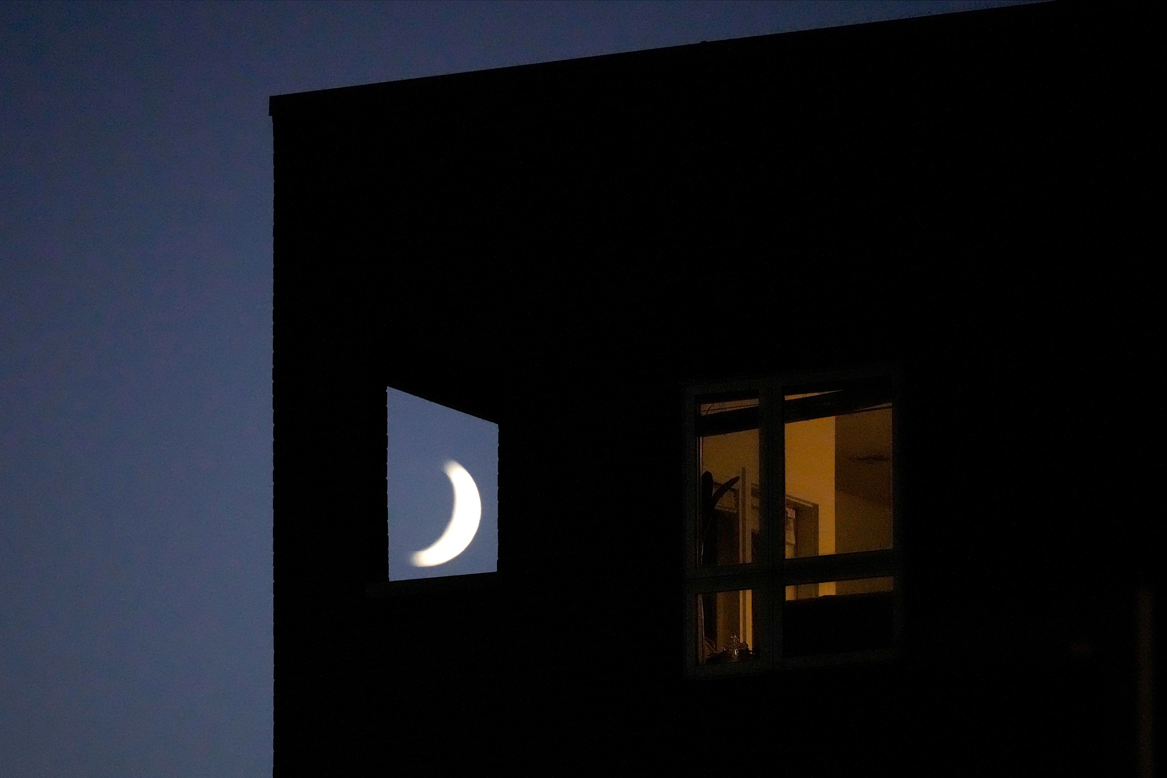 The crescent moon sets beyond an apartment building, Sunday, Oct. 6, 2024, in Kansas City, Mo. (AP Photo/Charlie Riedel)