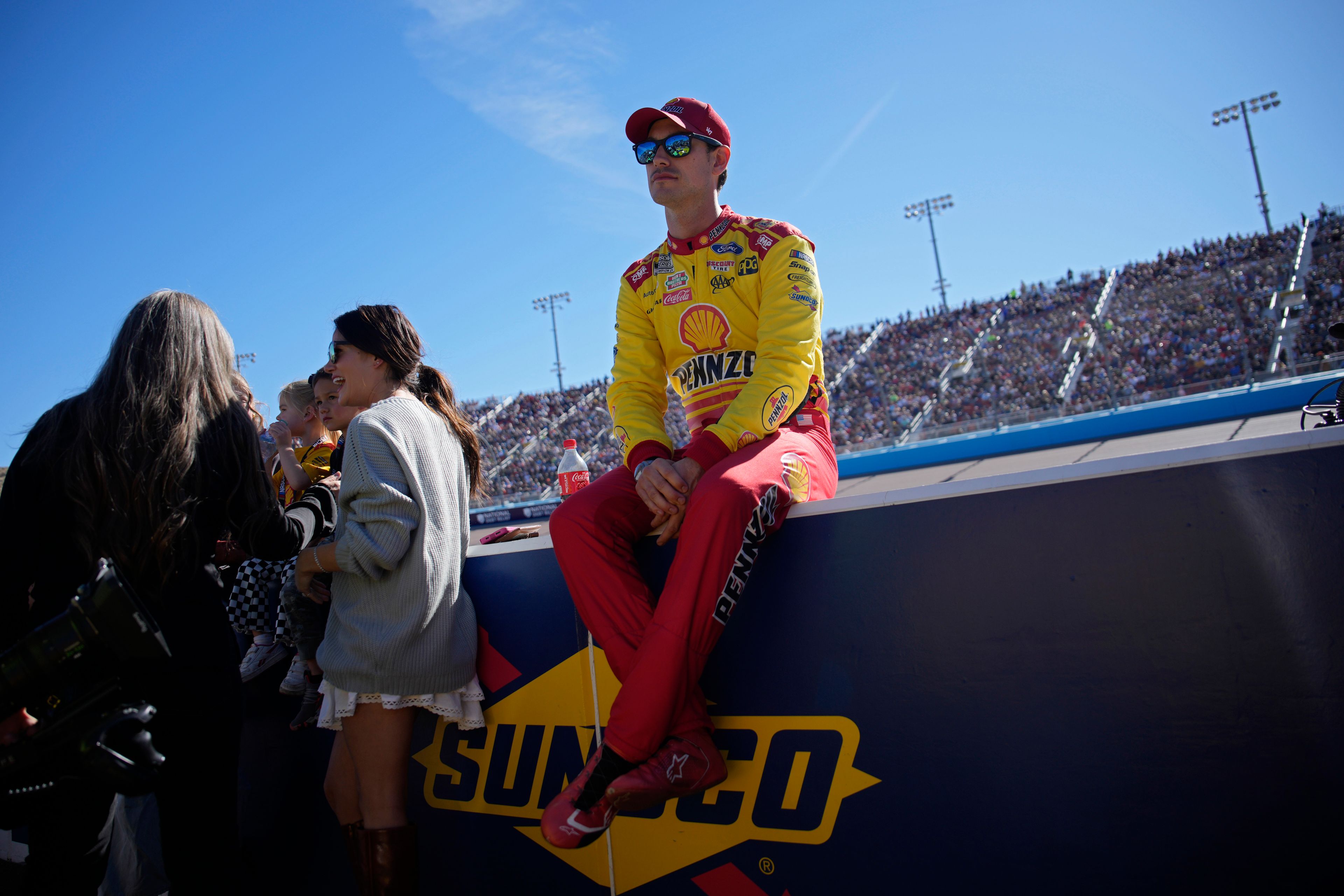 Joey Logano sits on the pit wall before a NASCAR Cup Series Championship auto race at Phoenix Raceway, Sunday, Nov. 10, 2024, in Avondale, Ariz. (AP Photo/John Locher)