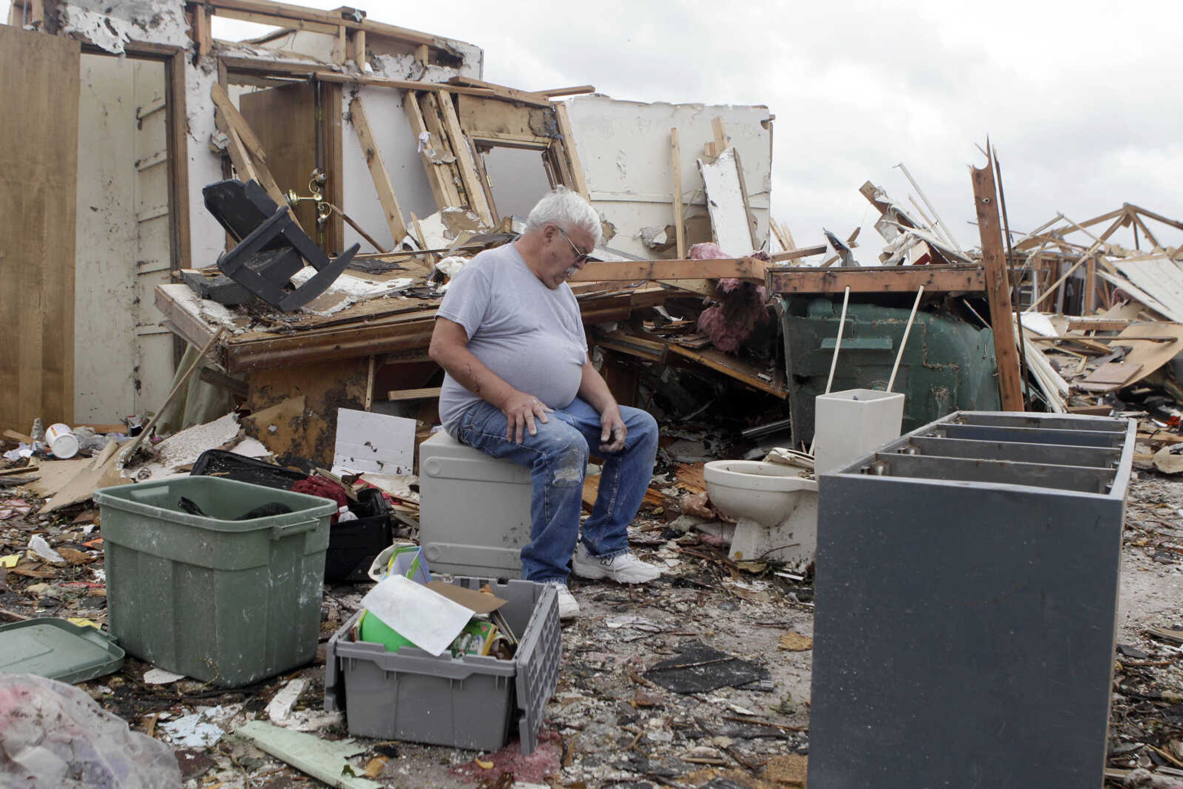 Kenneth Thomas sits on a safe in what was his living room Wednesday, May 25, 2011, in Joplin , Mo. Thomas took shelter with his wife, Retha, in a bathroom located directly behind where he is seated when a massive tornado struck Joplin Sunday night. Both escaped with only minor injuries. (AP Photo/Jeff Roberson)