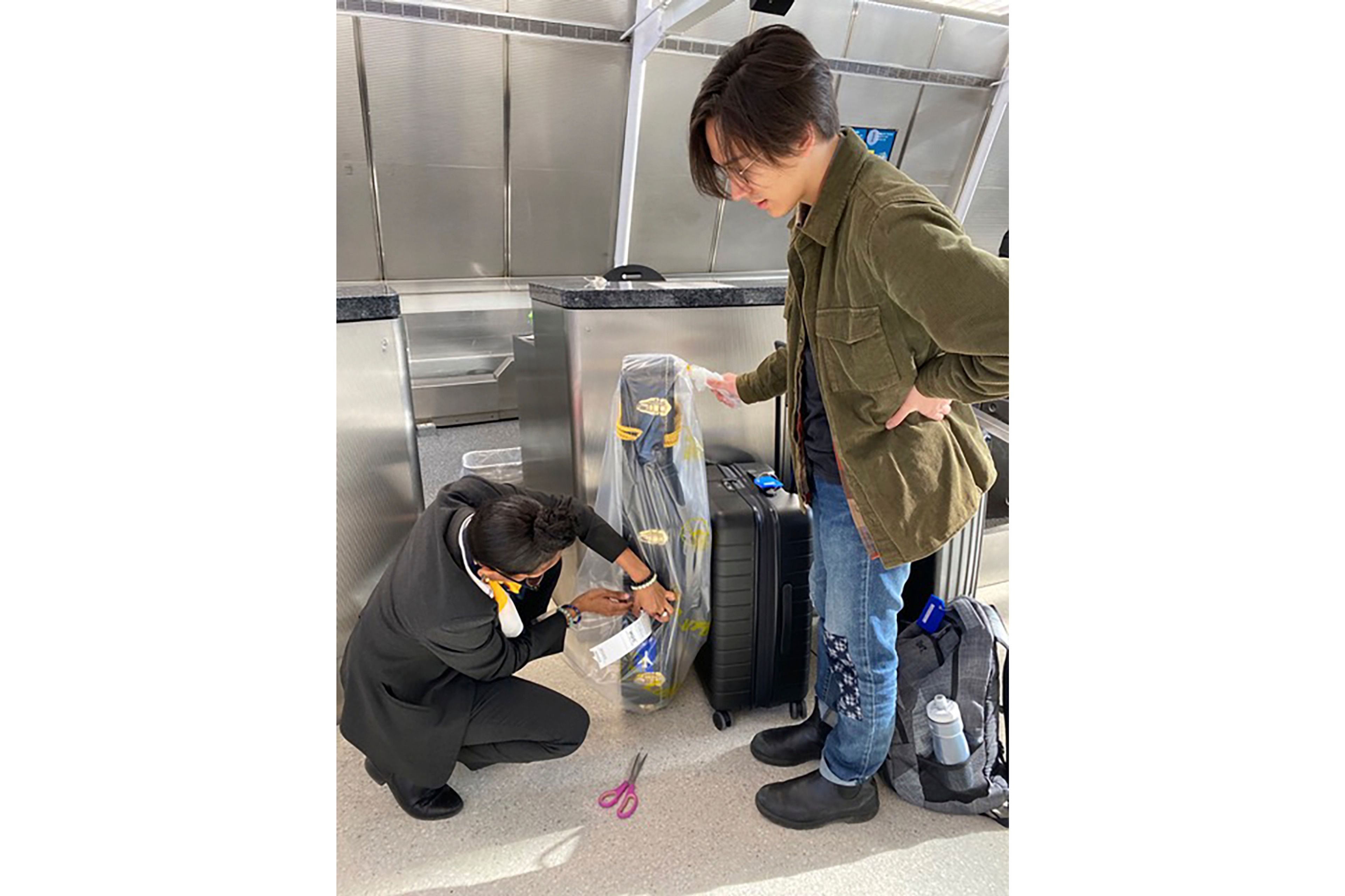 Yuji Kono watches as a Lufthansa staff member carefully wraps his banjo to be checked on a flight to Munich at John F. Kennedy International Airport in New York on March 1, 2024. (Katherine Roth via AP)