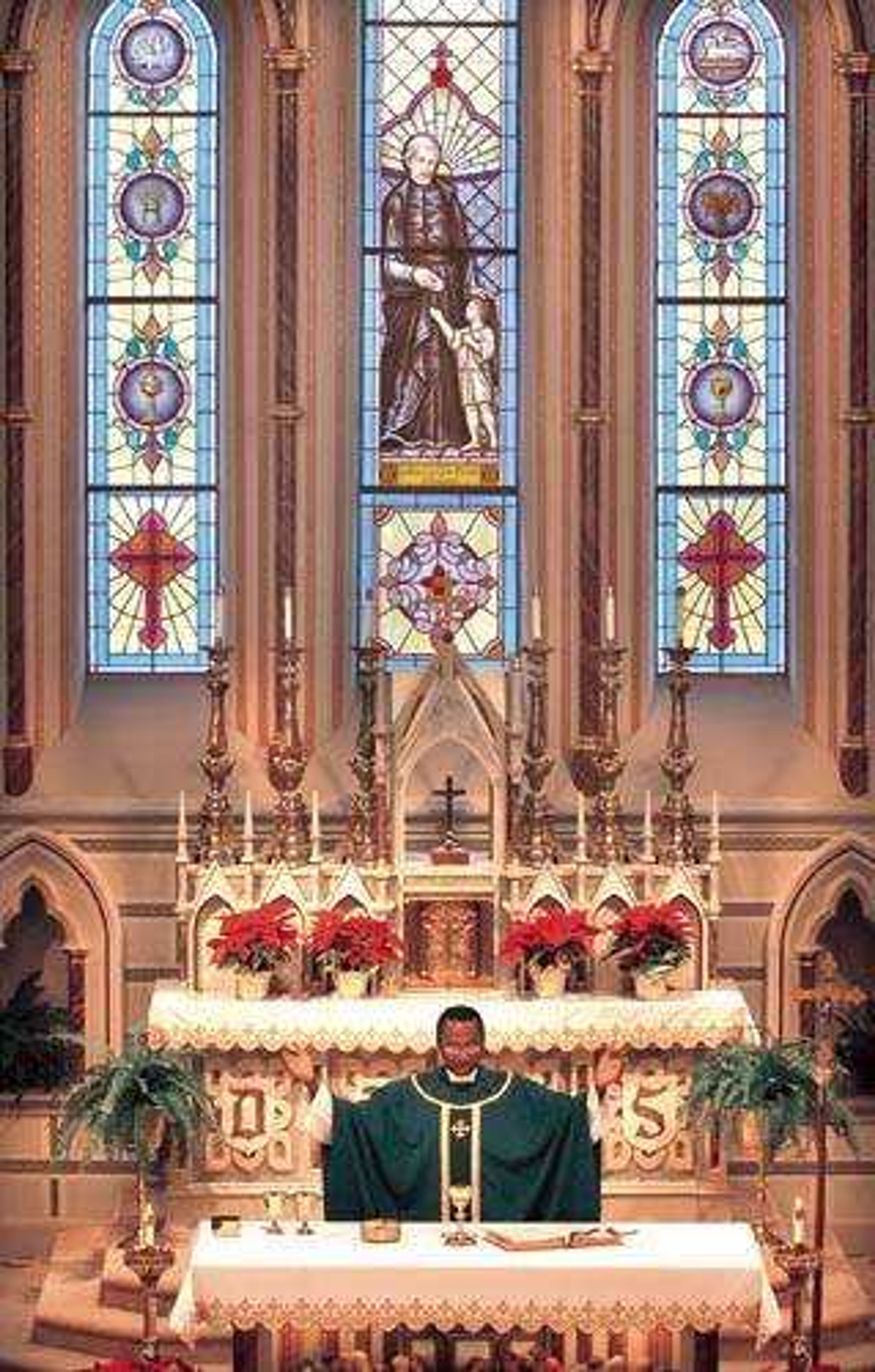 A stained-glass window depicts St. Vincent de Paul at Old St. Vincent's Church in Cape Girardeau. Below it, the Rev. Patrick Nwokoye of St. Mary's Cathedral celebrated Mass on Sunday. (Fred Lynch)